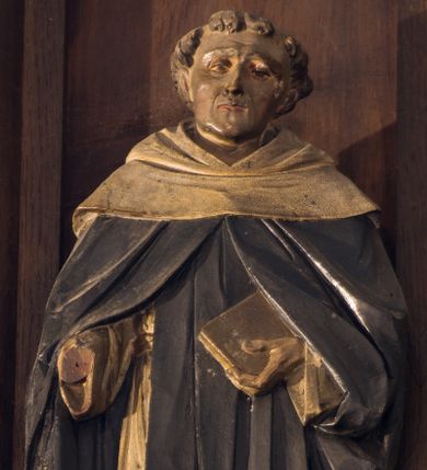 Zdjęcie nr 1: Rzeźba pełnoplastyczna przedstawiająca św. Dominika. Święty ukazany w postawie stojącej, frontalnie, z rękami wyciągniętymi przed siebie, w lewej trzyma księgę. Ma twarz o rysach dojrzałego mężczyzny, z długim i wąskim nosem, wąskimi ustami oraz delikatnie zmarszczonym czołem. Włosy krótkie, na czubku głowy zebrane w oddzielną kępkę. Święty ubrany jest w strój dominikański: biały habit, przewiązany sznurem z czarnym szkaplerzem oraz czarny płaszcz z białym kapturem, na stopach ma czarne buty. Księga w brązowej oprawie. 