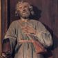 Zdjęcie nr 1: Rzeźba wolnostojąca, przedstawiająca św. Izydora. Święty ukazany w postawie stojącej z łopatą w prawej dłoni, z lewą dłonią złożoną na piersi, głowę delikatnie unosi do góry. Ma podłużną twarz, z wyraźnie zaznaczonymi kośćmi policzkowymi, z długim i wąskim nosem, ze wzrokiem skierowanym ku górze, okoloną krótką brodą i średniej długości, bujnymi włosami, zasłaniającymi uszy. Ubrany jest w jasnoniebieską tunikę z długimi rękawami o białych mankietach, sięgającą do kolan i przewiązaną w talii brązowym paskiem, żółte buty z wysokimi cholewami oraz skórzaną torbę przewieszoną przez prawe ramię.
