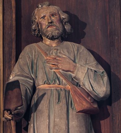 Zdjęcie nr 1: Rzeźba wolnostojąca, przedstawiająca św. Izydora. Święty ukazany w postawie stojącej z łopatą w prawej dłoni, z lewą dłonią złożoną na piersi, głowę delikatnie unosi do góry. Ma podłużną twarz, z wyraźnie zaznaczonymi kośćmi policzkowymi, z długim i wąskim nosem, ze wzrokiem skierowanym ku górze, okoloną krótką brodą i średniej długości, bujnymi włosami, zasłaniającymi uszy. Ubrany jest w jasnoniebieską tunikę z długimi rękawami o białych mankietach, sięgającą do kolan i przewiązaną w talii brązowym paskiem, żółte buty z wysokimi cholewami oraz skórzaną torbę przewieszoną przez prawe ramię.
