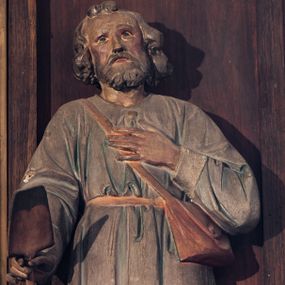 Zdjęcie nr 1: Rzeźba wolnostojąca, przedstawiająca św. Izydora. Święty ukazany w postawie stojącej z łopatą w prawej dłoni, z lewą dłonią złożoną na piersi, głowę delikatnie unosi do góry. Ma podłużną twarz, z wyraźnie zaznaczonymi kośćmi policzkowymi, z długim i wąskim nosem, ze wzrokiem skierowanym ku górze, okoloną krótką brodą i średniej długości, bujnymi włosami, zasłaniającymi uszy. Ubrany jest w jasnoniebieską tunikę z długimi rękawami o białych mankietach, sięgającą do kolan i przewiązaną w talii brązowym paskiem, żółte buty z wysokimi cholewami oraz skórzaną torbę przewieszoną przez prawe ramię.
