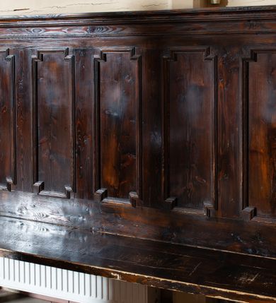 Zdjęcie nr 1: Drewniane ławki kolatorskie ustawione po obu stronach prezbiterium. Ławki ustawione na dwóch nóżkach, siedzisko proste w postaci prostej ławy. Zaplecek flankowany filarkami podtrzymującymi wyłamane, niepełne belkowanie, zamknięte gzymsem. Na osi filarków ustawione wazony. Zaplecek zdobiony pięcioma płycinami w kształcie stojących prostokątów o uszatych narożach. Ścianki boczne z przodu o wklęsło-wypukłym brzegu, sięgające do wysokości połowy zaplecka, na zakończeniu zdobione liśćmi stylizowanego akantu. Struktura pokryta bejcą.
