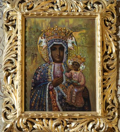 Zdjęcie nr 1: Obraz w kształcie stojącego prostokąta przedstawiający Matkę Boską Częstochowską o analogicznym układzie kompozycji jak oryginał. Maria ubrana jest w jasnoróżową suknię oraz niebieski maforion. Szaty są bogato dekorowane, malowanymi szlachetnymi kamieniami, na szyi Matka Boska ma zawieszony złoty krzyżyk. Chrystus ubrany jest w jasnoróżową sukienkę, również bogato dekorowaną. Maria i Dzieciątko mają na głowach założone korony, zdobione szlachetnymi kamieniami, podtrzymywane przez pary aniołków w białych tunikach. Tło w kolorze oliwkowym, wokół postaci rozmieszczone są sumarycznie oddane sceny. Po lewej stronie obrazu od dołu: Boże Narodzenie i Cierniem Ukoronowanie. Po prawej stronie od góry: Zwiastowanie, niżej Biczowanie Jezusa. Obraz umieszczony jest w profilowanej ramie zdobionej liśćmi wawrzynu, dookoła rzeźbione, ażurowe obramienie z liści akantu. 
