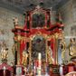Zdjęcie nr 1: Nastawa architektoniczna, dwukondygnacyjna, jednoosiowa z bramkami, na dwustrefowym cokole. Ołtarz kamienny, prostopadłościenny, w drewnianej obudowie, mensa drewniana z marmurowym portatylem. Antepedium w formie leżącego prostokąta ujętego profilowaną ramą; pole wyłożone tkaniną o kwiatowym wzorze z haftowanym medalionem w glorii z monogramem IHS; ujęty gałązkami lilii. Tabernakulum w formie drewnianej skrzynki z wypukłym frontem, obite srebrzoną blachą. Drzwiczki w kształcie stojącego prostokąta zamkniętego łukiem półkolistym, obwiedzione ramą. W polu aplikacja kielicha z hostią w glorii, ujętego kłosami zbóż; w przyłuczach ornament roślinny. Tabernakulum w architektonicznej obudowie tworzącej tron wystawienia; ujęte parą postumentów dekorowanych rocaille'owymi płycinami oraz parą filarów, przed którymi stoi para kolumn na postumentach utworzonych z ornamentalnych konsol. Podpory dźwigają belkowanie, wyłamane pośrodku, przerwane nad tabernakulum. Za tabernakulum niewielka ścianka zamknięta szczytem utworzonym z dwóch spływów wolutowych. Ze szczytu na belkowanie spływają ornamentalne woluty. Tron ujęty rocaille'owymi uszami. 
Pierwsza kondygnacja ujęta grupą zwielokrotnionych pilastrów, przed którymi stoją ustawione pod kątem cokoły z kolumnami o stylizowanych kapitelach kompozytowych, dźwigających pełne belkowanie, przerwane nad polem środkowym. Na tle pilastrów figury św. Jana Kantego po lewej stronie i św. Kazimierza po prawej. W polu środkowym obraz „Wszyscy Święci” ujęty profilowaną ramą w formie stojącego prostokąta, zamkniętego łukiem wklęsło-wypukłym z uskokami. Na zasuwie obraz przedstawiający Ukrzyżowanie Chrystusa. Druga kondygnacja w formie zbliżonej do kwadratu, flankowana przez zdwojone pilastry i spływy wolutowe, zamknięte szczytem z rocaille'owym kartuszem z napisem „OPŁUKALI / SWE SZATY / W KRWI / BARANKA / AP 7,14”. W polu obraz „Wniebowzięcie Najświętszej Marii Panny” ujęty profilowaną ramą w formie zbliżonej do kwadratu od dołu i od góry o wklęsło-wypukłym zarysie. Na zakończeniu spływów wolutowych usadzone dwie figury aniołów. Bramki w formie stojącego prostokąta ujętego parą pilastrów, dźwigających spływy wolutowe, podtrzymujące postumenty dla figur św. Stanisława po lewej stronie i św. Wojciecha po prawej. Przejścia w formie stojących prostokątów, zamkniętych stylizowanymi łukami segmentowymi nadwieszonymi. Całość dekorowana ornamentem rocaille'owym oraz różanymi zwisami w partii trzonów podpór, pierwsza kondygnacja flankowana rocaille'owymi, ażurowymi uszami. Struktura polichromowana w kolorze czerwonym, z malowanymi na czarno trzonami pilastrów i profilami, złoconymi kolumnami, profilami i ornamentyką oraz srebrzonymi detalami. Według dokumentacji konserwatorskiej na odwrociach baz kolumn znajdują się napisy „Leonora Olajassy żona organisty. 1887” oraz „Leonora Olajassy - organiścina. 1887”.