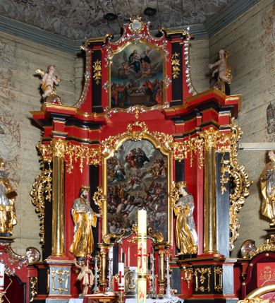 Zdjęcie nr 1: Nastawa architektoniczna, dwukondygnacyjna, jednoosiowa z bramkami, na dwustrefowym cokole. Ołtarz kamienny, prostopadłościenny, w drewnianej obudowie, mensa drewniana z marmurowym portatylem. Antepedium w formie leżącego prostokąta ujętego profilowaną ramą; pole wyłożone tkaniną o kwiatowym wzorze z haftowanym medalionem w glorii z monogramem IHS; ujęty gałązkami lilii. Tabernakulum w formie drewnianej skrzynki z wypukłym frontem, obite srebrzoną blachą. Drzwiczki w kształcie stojącego prostokąta zamkniętego łukiem półkolistym, obwiedzione ramą. W polu aplikacja kielicha z hostią w glorii, ujętego kłosami zbóż; w przyłuczach ornament roślinny. Tabernakulum w architektonicznej obudowie tworzącej tron wystawienia; ujęte parą postumentów dekorowanych rocaille'owymi płycinami oraz parą filarów, przed którymi stoi para kolumn na postumentach utworzonych z ornamentalnych konsol. Podpory dźwigają belkowanie, wyłamane pośrodku, przerwane nad tabernakulum. Za tabernakulum niewielka ścianka zamknięta szczytem utworzonym z dwóch spływów wolutowych. Ze szczytu na belkowanie spływają ornamentalne woluty. Tron ujęty rocaille'owymi uszami. 
Pierwsza kondygnacja ujęta grupą zwielokrotnionych pilastrów, przed którymi stoją ustawione pod kątem cokoły z kolumnami o stylizowanych kapitelach kompozytowych, dźwigających pełne belkowanie, przerwane nad polem środkowym. Na tle pilastrów figury św. Jana Kantego po lewej stronie i św. Kazimierza po prawej. W polu środkowym obraz „Wszyscy Święci” ujęty profilowaną ramą w formie stojącego prostokąta, zamkniętego łukiem wklęsło-wypukłym z uskokami. Na zasuwie obraz przedstawiający Ukrzyżowanie Chrystusa. Druga kondygnacja w formie zbliżonej do kwadratu, flankowana przez zdwojone pilastry i spływy wolutowe, zamknięte szczytem z rocaille'owym kartuszem z napisem „OPŁUKALI / SWE SZATY / W KRWI / BARANKA / AP 7,14”. W polu obraz „Wniebowzięcie Najświętszej Marii Panny” ujęty profilowaną ramą w formie zbliżonej do kwadratu od dołu i od góry o wklęsło-wypukłym zarysie. Na zakończeniu spływów wolutowych usadzone dwie figury aniołów. Bramki w formie stojącego prostokąta ujętego parą pilastrów, dźwigających spływy wolutowe, podtrzymujące postumenty dla figur św. Stanisława po lewej stronie i św. Wojciecha po prawej. Przejścia w formie stojących prostokątów, zamkniętych stylizowanymi łukami segmentowymi nadwieszonymi. Całość dekorowana ornamentem rocaille'owym oraz różanymi zwisami w partii trzonów podpór, pierwsza kondygnacja flankowana rocaille'owymi, ażurowymi uszami. Struktura polichromowana w kolorze czerwonym, z malowanymi na czarno trzonami pilastrów i profilami, złoconymi kolumnami, profilami i ornamentyką oraz srebrzonymi detalami. Według dokumentacji konserwatorskiej na odwrociach baz kolumn znajdują się napisy „Leonora Olajassy żona organisty. 1887” oraz „Leonora Olajassy - organiścina. 1887”.