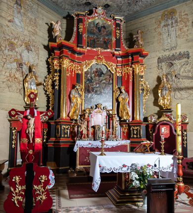 Zdjęcie nr 5: Nastawa architektoniczna, dwukondygnacyjna, jednoosiowa z bramkami, na dwustrefowym cokole. Ołtarz kamienny, prostopadłościenny, w drewnianej obudowie, mensa drewniana z marmurowym portatylem. Antepedium w formie leżącego prostokąta ujętego profilowaną ramą; pole wyłożone tkaniną o kwiatowym wzorze z haftowanym medalionem w glorii z monogramem IHS; ujęty gałązkami lilii. Tabernakulum w formie drewnianej skrzynki z wypukłym frontem, obite srebrzoną blachą. Drzwiczki w kształcie stojącego prostokąta zamkniętego łukiem półkolistym, obwiedzione ramą. W polu aplikacja kielicha z hostią w glorii, ujętego kłosami zbóż; w przyłuczach ornament roślinny. Tabernakulum w architektonicznej obudowie tworzącej tron wystawienia; ujęte parą postumentów dekorowanych rocaille'owymi płycinami oraz parą filarów, przed którymi stoi para kolumn na postumentach utworzonych z ornamentalnych konsol. Podpory dźwigają belkowanie, wyłamane pośrodku, przerwane nad tabernakulum. Za tabernakulum niewielka ścianka zamknięta szczytem utworzonym z dwóch spływów wolutowych. Ze szczytu na belkowanie spływają ornamentalne woluty. Tron ujęty rocaille'owymi uszami. 
Pierwsza kondygnacja ujęta grupą zwielokrotnionych pilastrów, przed którymi stoją ustawione pod kątem cokoły z kolumnami o stylizowanych kapitelach kompozytowych, dźwigających pełne belkowanie, przerwane nad polem środkowym. Na tle pilastrów figury św. Jana Kantego po lewej stronie i św. Kazimierza po prawej. W polu środkowym obraz „Wszyscy Święci” ujęty profilowaną ramą w formie stojącego prostokąta, zamkniętego łukiem wklęsło-wypukłym z uskokami. Na zasuwie obraz przedstawiający Ukrzyżowanie Chrystusa. Druga kondygnacja w formie zbliżonej do kwadratu, flankowana przez zdwojone pilastry i spływy wolutowe, zamknięte szczytem z rocaille'owym kartuszem z napisem „OPŁUKALI / SWE SZATY / W KRWI / BARANKA / AP 7,14”. W polu obraz „Wniebowzięcie Najświętszej Marii Panny” ujęty profilowaną ramą w formie zbliżonej do kwadratu od dołu i od góry o wklęsło-wypukłym zarysie. Na zakończeniu spływów wolutowych usadzone dwie figury aniołów. Bramki w formie stojącego prostokąta ujętego parą pilastrów, dźwigających spływy wolutowe, podtrzymujące postumenty dla figur św. Stanisława po lewej stronie i św. Wojciecha po prawej. Przejścia w formie stojących prostokątów, zamkniętych stylizowanymi łukami segmentowymi nadwieszonymi. Całość dekorowana ornamentem rocaille'owym oraz różanymi zwisami w partii trzonów podpór, pierwsza kondygnacja flankowana rocaille'owymi, ażurowymi uszami. Struktura polichromowana w kolorze czerwonym, z malowanymi na czarno trzonami pilastrów i profilami, złoconymi kolumnami, profilami i ornamentyką oraz srebrzonymi detalami. Według dokumentacji konserwatorskiej na odwrociach baz kolumn znajdują się napisy „Leonora Olajassy żona organisty. 1887” oraz „Leonora Olajassy - organiścina. 1887”.