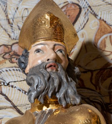 Zdjęcie nr 21: Nastawa architektoniczna, dwukondygnacyjna, jednoosiowa z bramkami, na dwustrefowym cokole. Ołtarz kamienny, prostopadłościenny, w drewnianej obudowie, mensa drewniana z marmurowym portatylem. Antepedium w formie leżącego prostokąta ujętego profilowaną ramą; pole wyłożone tkaniną o kwiatowym wzorze z haftowanym medalionem w glorii z monogramem IHS; ujęty gałązkami lilii. Tabernakulum w formie drewnianej skrzynki z wypukłym frontem, obite srebrzoną blachą. Drzwiczki w kształcie stojącego prostokąta zamkniętego łukiem półkolistym, obwiedzione ramą. W polu aplikacja kielicha z hostią w glorii, ujętego kłosami zbóż; w przyłuczach ornament roślinny. Tabernakulum w architektonicznej obudowie tworzącej tron wystawienia; ujęte parą postumentów dekorowanych rocaille'owymi płycinami oraz parą filarów, przed którymi stoi para kolumn na postumentach utworzonych z ornamentalnych konsol. Podpory dźwigają belkowanie, wyłamane pośrodku, przerwane nad tabernakulum. Za tabernakulum niewielka ścianka zamknięta szczytem utworzonym z dwóch spływów wolutowych. Ze szczytu na belkowanie spływają ornamentalne woluty. Tron ujęty rocaille'owymi uszami. 
Pierwsza kondygnacja ujęta grupą zwielokrotnionych pilastrów, przed którymi stoją ustawione pod kątem cokoły z kolumnami o stylizowanych kapitelach kompozytowych, dźwigających pełne belkowanie, przerwane nad polem środkowym. Na tle pilastrów figury św. Jana Kantego po lewej stronie i św. Kazimierza po prawej. W polu środkowym obraz „Wszyscy Święci” ujęty profilowaną ramą w formie stojącego prostokąta, zamkniętego łukiem wklęsło-wypukłym z uskokami. Na zasuwie obraz przedstawiający Ukrzyżowanie Chrystusa. Druga kondygnacja w formie zbliżonej do kwadratu, flankowana przez zdwojone pilastry i spływy wolutowe, zamknięte szczytem z rocaille'owym kartuszem z napisem „OPŁUKALI / SWE SZATY / W KRWI / BARANKA / AP 7,14”. W polu obraz „Wniebowzięcie Najświętszej Marii Panny” ujęty profilowaną ramą w formie zbliżonej do kwadratu od dołu i od góry o wklęsło-wypukłym zarysie. Na zakończeniu spływów wolutowych usadzone dwie figury aniołów. Bramki w formie stojącego prostokąta ujętego parą pilastrów, dźwigających spływy wolutowe, podtrzymujące postumenty dla figur św. Stanisława po lewej stronie i św. Wojciecha po prawej. Przejścia w formie stojących prostokątów, zamkniętych stylizowanymi łukami segmentowymi nadwieszonymi. Całość dekorowana ornamentem rocaille'owym oraz różanymi zwisami w partii trzonów podpór, pierwsza kondygnacja flankowana rocaille'owymi, ażurowymi uszami. Struktura polichromowana w kolorze czerwonym, z malowanymi na czarno trzonami pilastrów i profilami, złoconymi kolumnami, profilami i ornamentyką oraz srebrzonymi detalami. Według dokumentacji konserwatorskiej na odwrociach baz kolumn znajdują się napisy „Leonora Olajassy żona organisty. 1887” oraz „Leonora Olajassy - organiścina. 1887”.