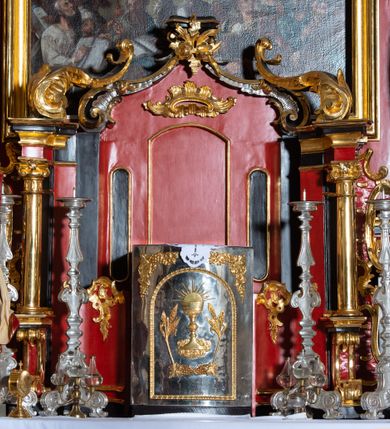 Zdjęcie nr 29: Nastawa architektoniczna, dwukondygnacyjna, jednoosiowa z bramkami, na dwustrefowym cokole. Ołtarz kamienny, prostopadłościenny, w drewnianej obudowie, mensa drewniana z marmurowym portatylem. Antepedium w formie leżącego prostokąta ujętego profilowaną ramą; pole wyłożone tkaniną o kwiatowym wzorze z haftowanym medalionem w glorii z monogramem IHS; ujęty gałązkami lilii. Tabernakulum w formie drewnianej skrzynki z wypukłym frontem, obite srebrzoną blachą. Drzwiczki w kształcie stojącego prostokąta zamkniętego łukiem półkolistym, obwiedzione ramą. W polu aplikacja kielicha z hostią w glorii, ujętego kłosami zbóż; w przyłuczach ornament roślinny. Tabernakulum w architektonicznej obudowie tworzącej tron wystawienia; ujęte parą postumentów dekorowanych rocaille&#039;owymi płycinami oraz parą filarów, przed którymi stoi para kolumn na postumentach utworzonych z ornamentalnych konsol. Podpory dźwigają belkowanie, wyłamane pośrodku, przerwane nad tabernakulum. Za tabernakulum niewielka ścianka zamknięta szczytem utworzonym z dwóch spływów wolutowych. Ze szczytu na belkowanie spływają ornamentalne woluty. Tron ujęty rocaille&#039;owymi uszami. 
Pierwsza kondygnacja ujęta grupą zwielokrotnionych pilastrów, przed którymi stoją ustawione pod kątem cokoły z kolumnami o stylizowanych kapitelach kompozytowych, dźwigających pełne belkowanie, przerwane nad polem środkowym. Na tle pilastrów figury św. Jana Kantego po lewej stronie i św. Kazimierza po prawej. W polu środkowym obraz „Wszyscy Święci” ujęty profilowaną ramą w formie stojącego prostokąta, zamkniętego łukiem wklęsło-wypukłym z uskokami. Na zasuwie obraz przedstawiający Ukrzyżowanie Chrystusa. Druga kondygnacja w formie zbliżonej do kwadratu, flankowana przez zdwojone pilastry i spływy wolutowe, zamknięte szczytem z rocaille&#039;owym kartuszem z napisem „OPŁUKALI / SWE SZATY / W KRWI / BARANKA / AP 7,14”. W polu obraz „Wniebowzięcie Najświętszej Marii Panny” ujęty profilowaną ramą w formie zbliżonej do kwadratu od dołu i od góry o wklęsło-wypukłym zarysie. Na zakończeniu spływów wolutowych usadzone dwie figury aniołów. Bramki w formie stojącego prostokąta ujętego parą pilastrów, dźwigających spływy wolutowe, podtrzymujące postumenty dla figur św. Stanisława po lewej stronie i św. Wojciecha po prawej. Przejścia w formie stojących prostokątów, zamkniętych stylizowanymi łukami segmentowymi nadwieszonymi. Całość dekorowana ornamentem rocaille&#039;owym oraz różanymi zwisami w partii trzonów podpór, pierwsza kondygnacja flankowana rocaille&#039;owymi, ażurowymi uszami. Struktura polichromowana w kolorze czerwonym, z malowanymi na czarno trzonami pilastrów i profilami, złoconymi kolumnami, profilami i ornamentyką oraz srebrzonymi detalami. Według dokumentacji konserwatorskiej na odwrociach baz kolumn znajdują się napisy „Leonora Olajassy żona organisty. 1887” oraz „Leonora Olajassy - organiścina. 1887”.