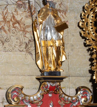 Zdjęcie nr 31: Nastawa architektoniczna, dwukondygnacyjna, jednoosiowa z bramkami, na dwustrefowym cokole. Ołtarz kamienny, prostopadłościenny, w drewnianej obudowie, mensa drewniana z marmurowym portatylem. Antepedium w formie leżącego prostokąta ujętego profilowaną ramą; pole wyłożone tkaniną o kwiatowym wzorze z haftowanym medalionem w glorii z monogramem IHS; ujęty gałązkami lilii. Tabernakulum w formie drewnianej skrzynki z wypukłym frontem, obite srebrzoną blachą. Drzwiczki w kształcie stojącego prostokąta zamkniętego łukiem półkolistym, obwiedzione ramą. W polu aplikacja kielicha z hostią w glorii, ujętego kłosami zbóż; w przyłuczach ornament roślinny. Tabernakulum w architektonicznej obudowie tworzącej tron wystawienia; ujęte parą postumentów dekorowanych rocaille&#039;owymi płycinami oraz parą filarów, przed którymi stoi para kolumn na postumentach utworzonych z ornamentalnych konsol. Podpory dźwigają belkowanie, wyłamane pośrodku, przerwane nad tabernakulum. Za tabernakulum niewielka ścianka zamknięta szczytem utworzonym z dwóch spływów wolutowych. Ze szczytu na belkowanie spływają ornamentalne woluty. Tron ujęty rocaille&#039;owymi uszami. 
Pierwsza kondygnacja ujęta grupą zwielokrotnionych pilastrów, przed którymi stoją ustawione pod kątem cokoły z kolumnami o stylizowanych kapitelach kompozytowych, dźwigających pełne belkowanie, przerwane nad polem środkowym. Na tle pilastrów figury św. Jana Kantego po lewej stronie i św. Kazimierza po prawej. W polu środkowym obraz „Wszyscy Święci” ujęty profilowaną ramą w formie stojącego prostokąta, zamkniętego łukiem wklęsło-wypukłym z uskokami. Na zasuwie obraz przedstawiający Ukrzyżowanie Chrystusa. Druga kondygnacja w formie zbliżonej do kwadratu, flankowana przez zdwojone pilastry i spływy wolutowe, zamknięte szczytem z rocaille&#039;owym kartuszem z napisem „OPŁUKALI / SWE SZATY / W KRWI / BARANKA / AP 7,14”. W polu obraz „Wniebowzięcie Najświętszej Marii Panny” ujęty profilowaną ramą w formie zbliżonej do kwadratu od dołu i od góry o wklęsło-wypukłym zarysie. Na zakończeniu spływów wolutowych usadzone dwie figury aniołów. Bramki w formie stojącego prostokąta ujętego parą pilastrów, dźwigających spływy wolutowe, podtrzymujące postumenty dla figur św. Stanisława po lewej stronie i św. Wojciecha po prawej. Przejścia w formie stojących prostokątów, zamkniętych stylizowanymi łukami segmentowymi nadwieszonymi. Całość dekorowana ornamentem rocaille&#039;owym oraz różanymi zwisami w partii trzonów podpór, pierwsza kondygnacja flankowana rocaille&#039;owymi, ażurowymi uszami. Struktura polichromowana w kolorze czerwonym, z malowanymi na czarno trzonami pilastrów i profilami, złoconymi kolumnami, profilami i ornamentyką oraz srebrzonymi detalami. Według dokumentacji konserwatorskiej na odwrociach baz kolumn znajdują się napisy „Leonora Olajassy żona organisty. 1887” oraz „Leonora Olajassy - organiścina. 1887”.