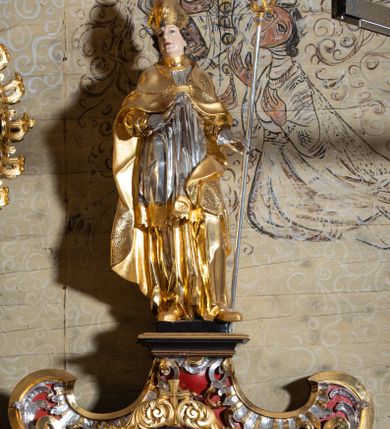 Zdjęcie nr 33: Nastawa architektoniczna, dwukondygnacyjna, jednoosiowa z bramkami, na dwustrefowym cokole. Ołtarz kamienny, prostopadłościenny, w drewnianej obudowie, mensa drewniana z marmurowym portatylem. Antepedium w formie leżącego prostokąta ujętego profilowaną ramą; pole wyłożone tkaniną o kwiatowym wzorze z haftowanym medalionem w glorii z monogramem IHS; ujęty gałązkami lilii. Tabernakulum w formie drewnianej skrzynki z wypukłym frontem, obite srebrzoną blachą. Drzwiczki w kształcie stojącego prostokąta zamkniętego łukiem półkolistym, obwiedzione ramą. W polu aplikacja kielicha z hostią w glorii, ujętego kłosami zbóż; w przyłuczach ornament roślinny. Tabernakulum w architektonicznej obudowie tworzącej tron wystawienia; ujęte parą postumentów dekorowanych rocaille'owymi płycinami oraz parą filarów, przed którymi stoi para kolumn na postumentach utworzonych z ornamentalnych konsol. Podpory dźwigają belkowanie, wyłamane pośrodku, przerwane nad tabernakulum. Za tabernakulum niewielka ścianka zamknięta szczytem utworzonym z dwóch spływów wolutowych. Ze szczytu na belkowanie spływają ornamentalne woluty. Tron ujęty rocaille'owymi uszami. 
Pierwsza kondygnacja ujęta grupą zwielokrotnionych pilastrów, przed którymi stoją ustawione pod kątem cokoły z kolumnami o stylizowanych kapitelach kompozytowych, dźwigających pełne belkowanie, przerwane nad polem środkowym. Na tle pilastrów figury św. Jana Kantego po lewej stronie i św. Kazimierza po prawej. W polu środkowym obraz „Wszyscy Święci” ujęty profilowaną ramą w formie stojącego prostokąta, zamkniętego łukiem wklęsło-wypukłym z uskokami. Na zasuwie obraz przedstawiający Ukrzyżowanie Chrystusa. Druga kondygnacja w formie zbliżonej do kwadratu, flankowana przez zdwojone pilastry i spływy wolutowe, zamknięte szczytem z rocaille'owym kartuszem z napisem „OPŁUKALI / SWE SZATY / W KRWI / BARANKA / AP 7,14”. W polu obraz „Wniebowzięcie Najświętszej Marii Panny” ujęty profilowaną ramą w formie zbliżonej do kwadratu od dołu i od góry o wklęsło-wypukłym zarysie. Na zakończeniu spływów wolutowych usadzone dwie figury aniołów. Bramki w formie stojącego prostokąta ujętego parą pilastrów, dźwigających spływy wolutowe, podtrzymujące postumenty dla figur św. Stanisława po lewej stronie i św. Wojciecha po prawej. Przejścia w formie stojących prostokątów, zamkniętych stylizowanymi łukami segmentowymi nadwieszonymi. Całość dekorowana ornamentem rocaille'owym oraz różanymi zwisami w partii trzonów podpór, pierwsza kondygnacja flankowana rocaille'owymi, ażurowymi uszami. Struktura polichromowana w kolorze czerwonym, z malowanymi na czarno trzonami pilastrów i profilami, złoconymi kolumnami, profilami i ornamentyką oraz srebrzonymi detalami. Według dokumentacji konserwatorskiej na odwrociach baz kolumn znajdują się napisy „Leonora Olajassy żona organisty. 1887” oraz „Leonora Olajassy - organiścina. 1887”.