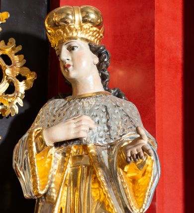 Zdjęcie nr 1: Rzeźba ścięta z tyłu, drążona, przedstawiająca św. Kazimierza królewicza. Święty ukazany w postawie stojącej w delikatnym kontrapoście, zwrócony trzy czwarte w prawo, z prawą ręką złożoną na piersi, a lewą wyciągniętą przed siebie. Twarz młodzieńcza, owalna o pełnych policzkach, z wyraźnie zaznaczonym podbródkiem, dużym nosem i małymi oczami. Włosy długie, ciemnobrązowe i kręcone opadają dużymi falami na plecy. Święty jest ubrany w długą, złoconą suknię oraz królewski płaszcz z gronostajową pelerynką i podbiciem. Na stopach ma założone buty, a na głowie mitrę książęcą. Polichromia naturalistyczna w odsłoniętych partiach ciała, szaty złocone i srebrzone.
