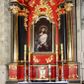 Zdjęcie nr 1: Tabernakulum w kształcie prostopadłościennej skrzynki na niskim cokole, z lekko wypukłą ścianką przednią, flankowaną parą pilastrów z przylegającymi do nich półkolumienkami wspierającymi wyłamujący się ponad nimi gzyms, lekko wypukły w środkowej partii. Drzwiczki w kształcie stojącego prostokąta, ujęte profilowaną i złoconą ramą, zdobione grawerowanym, złoconym i srebrzonym przedstawieniem krzyża łacińskiego z wiązkami promieni wychodzących z miejsca przecięcia ramion oraz monogramem IHS. Struktura polichromowana w kolorze czerwieni i czerni, partie detalu architektonicznego złocone.   
