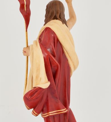 Zdjęcie nr 4: Rzeźba Chrystusa Zmartwychwstałego pełnoplastyczna, wolnostojąca. Chrystus ukazany jest w całej postaci, ustawiony frontalnie, w delikatnym kontrapoście; prawą, wysoko uniesioną ręką czyni gest błogosławieństwa, a w lewej trzyma chorągiew o długim drzewcu zakończonym krzyżem, na czerwonej tkaninie widnieje złoty krzyż. Chrystus ma podłużną twarz z długim i wąskim nosem, wzrokiem skierowanym w dal, okoloną krótką i ciemną brodą, rozdzieloną na końcu w dwa pukle oraz długie, ciemnobrązowe włosy, które opadają na plecy i ramiona. Chrystus jest ubrany w czerwony płaszcz z jasnobeżową podszewką i złoconą bordiurą, przerzucony przez lewe ramię i odsłaniający prawe ramię oraz nagi tors z drugą połą płaszcza zarzuconą na lewą rękę. Na dłoniach, stopach i boku zaznaczone są ślady męki. Polichromia ciała jest naturalistyczna. Rzeźba ustawiona jest na dwóch ukośnie ustawionych, prostopadłościennych kostkach. 