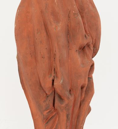 Zdjęcie nr 6: Rzeźba Chrystusa Zmartwychwstałego pełnoplastyczna, wolnostojąca, ustawiona na niskim, półkolistym cokole. Chrystus ukazany w całej postaci, ustawiony frontalnie, prawą ręką czyni gest błogosławieństwa, lewa niezachowana. Twarz podłużna, z długim nosem i małymi oczami, wysokim czołem, okolona krótką i brązową brodą, rozdzieloną na końcu w dwa małe pukle. Włosy długie, brązowe opadające na ramiona i plecy równolegle ułożonymi lokami skręconymi na końcu. Chrystus ubrany jest w czerwony płaszcz z zieloną podszewką, spięty na dekolcie złotą broszką, odsłaniający klatkę piersiową i nogi, otaczający figurę, z prawą połą przerzuconą przez lewe przedramię. Na dłoniach, stopach i boku ma delikatnie zaznaczone ślady męki. Polichromia ciała jest naturalistyczna, lamówka płaszcza złocona. 
