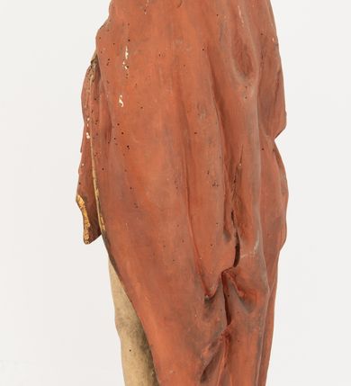 Zdjęcie nr 8: Rzeźba Chrystusa Zmartwychwstałego pełnoplastyczna, wolnostojąca, ustawiona na niskim, półkolistym cokole. Chrystus ukazany w całej postaci, ustawiony frontalnie, prawą ręką czyni gest błogosławieństwa, lewa niezachowana. Twarz podłużna, z długim nosem i małymi oczami, wysokim czołem, okolona krótką i brązową brodą, rozdzieloną na końcu w dwa małe pukle. Włosy długie, brązowe opadające na ramiona i plecy równolegle ułożonymi lokami skręconymi na końcu. Chrystus ubrany jest w czerwony płaszcz z zieloną podszewką, spięty na dekolcie złotą broszką, odsłaniający klatkę piersiową i nogi, otaczający figurę, z prawą połą przerzuconą przez lewe przedramię. Na dłoniach, stopach i boku ma delikatnie zaznaczone ślady męki. Polichromia ciała jest naturalistyczna, lamówka płaszcza złocona. 
