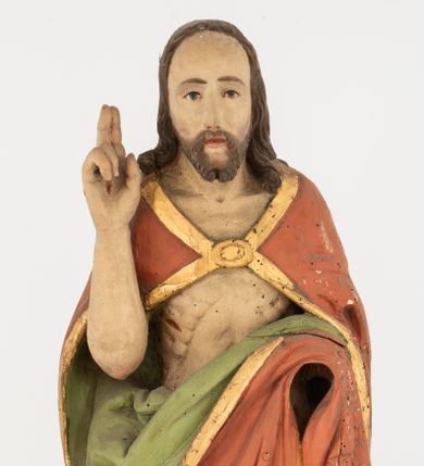 Zdjęcie nr 1: Rzeźba Chrystusa Zmartwychwstałego pełnoplastyczna, wolnostojąca, ustawiona na niskim, półkolistym cokole. Chrystus ukazany w całej postaci, ustawiony frontalnie, prawą ręką czyni gest błogosławieństwa, lewa niezachowana. Twarz podłużna, z długim nosem i małymi oczami, wysokim czołem, okolona krótką i brązową brodą, rozdzieloną na końcu w dwa małe pukle. Włosy długie, brązowe opadające na ramiona i plecy równolegle ułożonymi lokami skręconymi na końcu. Chrystus ubrany jest w czerwony płaszcz z zieloną podszewką, spięty na dekolcie złotą broszką, odsłaniający klatkę piersiową i nogi, otaczający figurę, z prawą połą przerzuconą przez lewe przedramię. Na dłoniach, stopach i boku ma delikatnie zaznaczone ślady męki. Polichromia ciała jest naturalistyczna, lamówka płaszcza złocona. 
