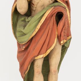 Zdjęcie nr 1: Rzeźba Chrystusa Zmartwychwstałego pełnoplastyczna, wolnostojąca, ustawiona na niskim, półkolistym cokole. Chrystus ukazany w całej postaci, ustawiony frontalnie, prawą ręką czyni gest błogosławieństwa, lewa niezachowana. Twarz podłużna, z długim nosem i małymi oczami, wysokim czołem, okolona krótką i brązową brodą, rozdzieloną na końcu w dwa małe pukle. Włosy długie, brązowe opadające na ramiona i plecy równolegle ułożonymi lokami skręconymi na końcu. Chrystus ubrany jest w czerwony płaszcz z zieloną podszewką, spięty na dekolcie złotą broszką, odsłaniający klatkę piersiową i nogi, otaczający figurę, z prawą połą przerzuconą przez lewe przedramię. Na dłoniach, stopach i boku ma delikatnie zaznaczone ślady męki. Polichromia ciała jest naturalistyczna, lamówka płaszcza złocona. 
