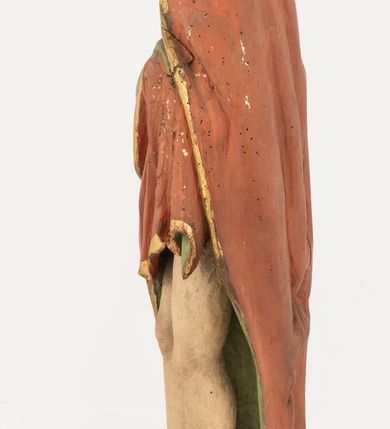 Zdjęcie nr 9: Rzeźba Chrystusa Zmartwychwstałego pełnoplastyczna, wolnostojąca, ustawiona na niskim, półkolistym cokole. Chrystus ukazany w całej postaci, ustawiony frontalnie, prawą ręką czyni gest błogosławieństwa, lewa niezachowana. Twarz podłużna, z długim nosem i małymi oczami, wysokim czołem, okolona krótką i brązową brodą, rozdzieloną na końcu w dwa małe pukle. Włosy długie, brązowe opadające na ramiona i plecy równolegle ułożonymi lokami skręconymi na końcu. Chrystus ubrany jest w czerwony płaszcz z zieloną podszewką, spięty na dekolcie złotą broszką, odsłaniający klatkę piersiową i nogi, otaczający figurę, z prawą połą przerzuconą przez lewe przedramię. Na dłoniach, stopach i boku ma delikatnie zaznaczone ślady męki. Polichromia ciała jest naturalistyczna, lamówka płaszcza złocona. 
