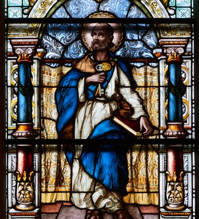 Zdjęcie nr 1: Witraż w kształcie stojącego prostokąta, zamkniętego łukiem odcinkowym. W centrum kompozycji ukazany jest św. Piotr wewnątrz dekoracyjnej aediculi. Święty przedstawiony jest frontalnie, w lewej dłoni trzyma opartą o biodro księgę, a w prawej dwa klucze, przyciśnięte do piersi, głowa uniesiona lekko do góry. Twarz szeroka z wysokim czołem z zaznaczoną łysiną na głowie, okolona bujną, krótką brodą. Święty ubrany jest w białą suknię, przewiązaną w pasie; niebieski płaszcz ze złotą podszewką, spięty na lewym ramieniu zieloną fibulą oraz sandały na stopach; wokół głowy ma kolisty nimb, wypełniony świetlistymi promieniami i złotymi zdobieniami. Aedicula wsparta jest na parach kolumn oraz stojących za nimi filarów, ustawionych na dwustopniowych cokołach. Podpory podtrzymują zwieńczenie z łukiem odcinkowym z przodu. W tle na prostym drążku, zawieszona jest drapowana, złota kotara ze złotymi frędzlami; podłoga ułożona z brązowym płytek. Cokoły kolumn dekorowane są płycinami, wypełnionymi rozetami i wolutami. Kolumny w połowie przedzielone są opaską, u dołu zdobione stylizowanymi liśćmi akantu, a u góry zielonym festonem. W dolnej części kolumny są koloru czerwonego, w górnej niebieskiego; kapitele kompozytowe. Trzony filarów zdobione prostokątnymi płycinami, wypełnionymi roślinną dekoracją. Łuk zdobiony jest złoconą wicią roślinną i astragalem, w kluczu znajduje się uskrzydlona główka aniołka z czerwonymi skrzydłami. Zwieńczenie dwustopniowe, bogato dekorowane wolutkami i liśćmi akantu, na szczycie przerwany przyczółek, a po środku wazon. W dolnej partii witrażu, pomiędzy cokołami aediculi ozdobny kartusz zdobiony stylizowanym ornamentem okuciowym z prostokątną płyciną w polu z napisem: „S[ANC]T[US] PETRUS” oraz sygnatura artysty Georga Boosa z Monachium.


