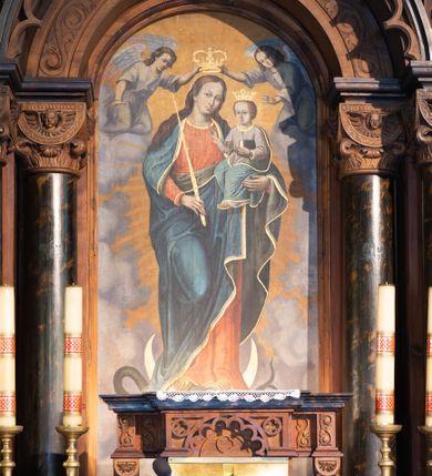 Zdjęcie nr 4: Ołtarz architektoniczny, jednokondygnacyjny, trójosiowy, ze zwieńczeniem. Ołtarz prostopadłościenny, kamienny, ustawiony na podstawie, w drewnianej obudowie. Mensa drewniana z marmurowym portatylem. Tabernakulum w formie prostopadłościennej metalowej skrzynki w drewnianej obudowie. Metalowe drzwiczki zdobi motyw kielicha eucharystycznego. Tabernakulum ujęte jest po bokach parą wolnostojących kolumienek wspierających wysunięte ponad nimi, wieńczące je belkowanie z wysokim fryzem. W partii belkowania nad drzwiczkami arkada dekorowana koronką i maswerkowymi rozetami w przyłuczach. Na belkowaniu tron wystawienia, na którym ustawiony krucyfiks. Osadzona na cokole nastawa ołtarza ma formę trójprzelotowego łuku triumfalnego. Część środkowa w kształcie półkolistej arkady wspartej na dwóch parach kolumn, z których wewnętrzne są cofnięte względem zewnętrznych. Arkady artykułujące osie boczne są mniejsze, ujmuje je po jednej parze kolumn wspierających zryzalitowane cokoły flankujące pola wypełnione fryzem arkadkowym. Zwieńczenie ołtarza ujmuje para kolumn wspierających gzyms w formie trójkątnego przyczółka. Pola cokołów retabulum zdobi stylizowana ornamentyka roślinna, kapitele kolumn oraz zwieńczenia arkad osi bocznych motywy uskrzydlonych główek anielskich. Krawędź łuku arkady części środkowej obiega fryz arkadkowy. W przyłuczach arkady ażurowe maswerki. Gzyms wieńczący kondygnację retabulum ujmuje motyw konsolek w formie liści akantu. Zwieńczenie flankowane parą ażurowych uszaków w postaci ornamentu roślinnego, parą figur aniołów oraz dwiema parami wazonów. Pole przyczółka wypełnia płaskorzeźbione przedstawienie gołębicy Ducha Świętego na tle promienistej glorii. Po jego bokach znajduje się para wazonów, szczyt jest w formie krzyża. Zwieńczenie flankują dwie figury aniołów ujęte po bokach dwoma parami wazonów.  
Pole części środkowej w kształcie stojącego prostokąta zamkniętego półkoliście z obrazem Madonny z Dzieciątkiem. W niszach osi bocznych są figury św. Piotra po prawej stronie i św. Pawła po lewej. Kształt pola zwieńczenia jest zbliżony do kwadratu ujętego szerokim obramieniem zdobionym parami S-kształtnych wolut. W środku znajduje się tondo z płaskorzeźbionym przedstawieniem anioła trzymającego kwiat lilii. 

Struktura retabulum utrzymana w kolorze drewna, trzony kolumn i część detali architektonicznych marmoryzowane, tła osi bocznych polichromowane w kolorze ciemnoniebieskim.    

