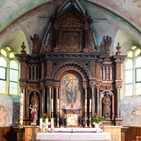 Zdjęcie nr 1: Ołtarz architektoniczny, jednokondygnacyjny, trójosiowy, ze zwieńczeniem. Ołtarz prostopadłościenny, kamienny, ustawiony na podstawie, w drewnianej obudowie. Mensa drewniana z marmurowym portatylem. Tabernakulum w formie prostopadłościennej metalowej skrzynki w drewnianej obudowie. Metalowe drzwiczki zdobi motyw kielicha eucharystycznego. Tabernakulum ujęte jest po bokach parą wolnostojących kolumienek wspierających wysunięte ponad nimi, wieńczące je belkowanie z wysokim fryzem. W partii belkowania nad drzwiczkami arkada dekorowana koronką i maswerkowymi rozetami w przyłuczach. Na belkowaniu tron wystawienia, na którym ustawiony krucyfiks. Osadzona na cokole nastawa ołtarza ma formę trójprzelotowego łuku triumfalnego. Część środkowa w kształcie półkolistej arkady wspartej na dwóch parach kolumn, z których wewnętrzne są cofnięte względem zewnętrznych. Arkady artykułujące osie boczne są mniejsze, ujmuje je po jednej parze kolumn wspierających zryzalitowane cokoły flankujące pola wypełnione fryzem arkadkowym. Zwieńczenie ołtarza ujmuje para kolumn wspierających gzyms w formie trójkątnego przyczółka. Pola cokołów retabulum zdobi stylizowana ornamentyka roślinna, kapitele kolumn oraz zwieńczenia arkad osi bocznych motywy uskrzydlonych główek anielskich. Krawędź łuku arkady części środkowej obiega fryz arkadkowy. W przyłuczach arkady ażurowe maswerki. Gzyms wieńczący kondygnację retabulum ujmuje motyw konsolek w formie liści akantu. Zwieńczenie flankowane parą ażurowych uszaków w postaci ornamentu roślinnego, parą figur aniołów oraz dwiema parami wazonów. Pole przyczółka wypełnia płaskorzeźbione przedstawienie gołębicy Ducha Świętego na tle promienistej glorii. Po jego bokach znajduje się para wazonów, szczyt jest w formie krzyża. Zwieńczenie flankują dwie figury aniołów ujęte po bokach dwoma parami wazonów.  
Pole części środkowej w kształcie stojącego prostokąta zamkniętego półkoliście z obrazem Madonny z Dzieciątkiem. W niszach osi bocznych są figury św. Piotra po prawej stronie i św. Pawła po lewej. Kształt pola zwieńczenia jest zbliżony do kwadratu ujętego szerokim obramieniem zdobionym parami S-kształtnych wolut. W środku znajduje się tondo z płaskorzeźbionym przedstawieniem anioła trzymającego kwiat lilii. 

Struktura retabulum utrzymana w kolorze drewna, trzony kolumn i część detali architektonicznych marmoryzowane, tła osi bocznych polichromowane w kolorze ciemnoniebieskim.    


