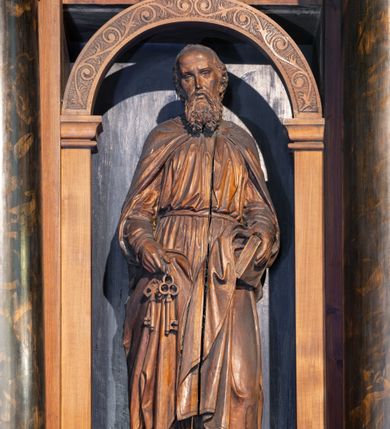 Zdjęcie nr 6: Ołtarz architektoniczny, jednokondygnacyjny, trójosiowy, ze zwieńczeniem. Ołtarz prostopadłościenny, kamienny, ustawiony na podstawie, w drewnianej obudowie. Mensa drewniana z marmurowym portatylem. Tabernakulum w formie prostopadłościennej metalowej skrzynki w drewnianej obudowie. Metalowe drzwiczki zdobi motyw kielicha eucharystycznego. Tabernakulum ujęte jest po bokach parą wolnostojących kolumienek wspierających wysunięte ponad nimi, wieńczące je belkowanie z wysokim fryzem. W partii belkowania nad drzwiczkami arkada dekorowana koronką i maswerkowymi rozetami w przyłuczach. Na belkowaniu tron wystawienia, na którym ustawiony krucyfiks. Osadzona na cokole nastawa ołtarza ma formę trójprzelotowego łuku triumfalnego. Część środkowa w kształcie półkolistej arkady wspartej na dwóch parach kolumn, z których wewnętrzne są cofnięte względem zewnętrznych. Arkady artykułujące osie boczne są mniejsze, ujmuje je po jednej parze kolumn wspierających zryzalitowane cokoły flankujące pola wypełnione fryzem arkadkowym. Zwieńczenie ołtarza ujmuje para kolumn wspierających gzyms w formie trójkątnego przyczółka. Pola cokołów retabulum zdobi stylizowana ornamentyka roślinna, kapitele kolumn oraz zwieńczenia arkad osi bocznych motywy uskrzydlonych główek anielskich. Krawędź łuku arkady części środkowej obiega fryz arkadkowy. W przyłuczach arkady ażurowe maswerki. Gzyms wieńczący kondygnację retabulum ujmuje motyw konsolek w formie liści akantu. Zwieńczenie flankowane parą ażurowych uszaków w postaci ornamentu roślinnego, parą figur aniołów oraz dwiema parami wazonów. Pole przyczółka wypełnia płaskorzeźbione przedstawienie gołębicy Ducha Świętego na tle promienistej glorii. Po jego bokach znajduje się para wazonów, szczyt jest w formie krzyża. Zwieńczenie flankują dwie figury aniołów ujęte po bokach dwoma parami wazonów.  
Pole części środkowej w kształcie stojącego prostokąta zamkniętego półkoliście z obrazem Madonny z Dzieciątkiem. W niszach osi bocznych są figury św. Piotra po prawej stronie i św. Pawła po lewej. Kształt pola zwieńczenia jest zbliżony do kwadratu ujętego szerokim obramieniem zdobionym parami S-kształtnych wolut. W środku znajduje się tondo z płaskorzeźbionym przedstawieniem anioła trzymającego kwiat lilii. 

Struktura retabulum utrzymana w kolorze drewna, trzony kolumn i część detali architektonicznych marmoryzowane, tła osi bocznych polichromowane w kolorze ciemnoniebieskim.    

