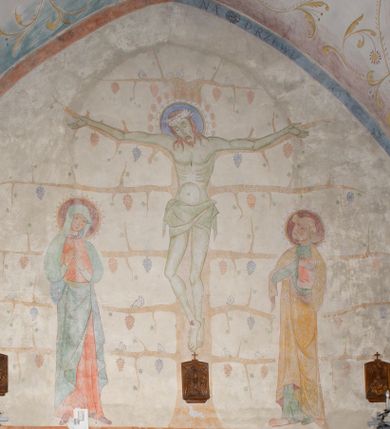 Zdjęcie nr 1: Polichromia obejmuje powierzchnie sklepień i ścian prezbiterium oraz korpusu nawowego. W partii sklepień przybiera formę ulistnionych wici roślinnych w kolorze żółtym z kolorowymi kwiatkami, na tłach w kolorach niebieskim, fioletowym czy zielonym. Polichromia ścian prezbiterium jest dwustrefowa – w dolnej partii, do wysokości okien, na monochromatycznych tłach w kolorze m.in. brązu czy granatu znajdują się sceny figuralne – na południowo-wschodniej ścianie jest Pieta, na południowej – Wieczerza w Emaus z siedzącym przy stole Jezusem pomiędzy dwoma uczniami. Pozostałą powierzchnię ścian zajmują sceny ukazane na białym tle. Na ścianie północnej Ukrzyżowanie, gdzie Jezus jest przedstawiony na krzyżu w formie Drzewa Życia, po lewej stronie stoi Matka Boska, po prawej św. Jan Ewangelista. Na południowej ścianie został ukazany Chrystus Zmartwychwstały na tle promienistej glorii. Postaci charakteryzują smukłe, schematycznie opracowane sylwetki, drapowania szat – syntetyzm, natomiast kolorystyka utrzymana jest w odcieniach pastelowych.   