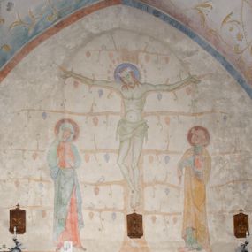 Zdjęcie nr 1: Polichromia obejmuje powierzchnie sklepień i ścian prezbiterium oraz korpusu nawowego. W partii sklepień przybiera formę ulistnionych wici roślinnych w kolorze żółtym z kolorowymi kwiatkami, na tłach w kolorach niebieskim, fioletowym czy zielonym. Polichromia ścian prezbiterium jest dwustrefowa – w dolnej partii, do wysokości okien, na monochromatycznych tłach w kolorze m.in. brązu czy granatu znajdują się sceny figuralne – na południowo-wschodniej ścianie jest Pieta, na południowej – Wieczerza w Emaus z siedzącym przy stole Jezusem pomiędzy dwoma uczniami. Pozostałą powierzchnię ścian zajmują sceny ukazane na białym tle. Na ścianie północnej Ukrzyżowanie, gdzie Jezus jest przedstawiony na krzyżu w formie Drzewa Życia, po lewej stronie stoi Matka Boska, po prawej św. Jan Ewangelista. Na południowej ścianie został ukazany Chrystus Zmartwychwstały na tle promienistej glorii. Postaci charakteryzują smukłe, schematycznie opracowane sylwetki, drapowania szat – syntetyzm, natomiast kolorystyka utrzymana jest w odcieniach pastelowych.   