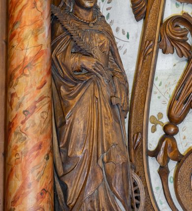 Zdjęcie nr 3: Ołtarz architektoniczny, jednokondygnacyjny, jednoosiowy ze zwieńczeniem. Ołtarz prostopadłościenny z drewnianą mensą, po bokach ujęty uskokowo. Retabulum osadzone na niewysokim, podwójnie zryzalitowanym po bokach cokole, skrajne partie ustawione ukośnie. Część środkowa w formie półkoliście zamkniętej arkady wspartej na parze kolumn i ujętej parą pilastrów. Całość wieńczy wyłamujące się w części środkowej belkowanie. Zwieńczenie ujmuje para kolumn osadzonych na niewielkich cokołach i wspierających gzyms w kształcie trójkątnego przyczółka. Pola uskokowych boków ołtarza zdobią motywy S-kształtnych, ulistnionych wolut, pole antepedium wypełnia fryz arkadkowy. Partie cokołu retabulum zdobią motywy rozet. W kapitelach kolumn jest dekoracja w formie uskrzydlonych główek anielskich. Łuk arkady zdobi ażurowy fryz arkadkowy, natomiast górne pola tej części retabulum motywy czwórliści i S-kształtnych, ulistnionych wolut. Zarówno środkową część retabulum, jak i zwieńczenie ujmują po bokach pary ażurowych uszaków w formie wici roślinnej. W polu przyczółka jest płaskorzeźbiona promienista gloria z monogramem maryjnym pośrodku. Szczyt zwieńczenia w formie krzyża. Pole arkady części środkowej retabulum wypełnia płaskorzeźbiona sylwetka św. Michała Archanioła, natomiast po bokach, na tle pilastrów została ustawiona para figur św. Katarzyny Aleksandryjskiej po prawej stronie i św. Andrzeja po lewej. Pole zwieńczenia w kształcie zbliżonym do kwadratu, ujęte szerokim obramieniem zdobionym ażurowym ornamentem w formie S-kształtnych, ulistnionych wolut. W środku jest tondo z płaskorzeźbionym wizerunkiem św. Jana Chrzciciela. 
Struktura retabulum utrzymana w kolorze drewna, trzony kolumn i część detali architektonicznych marmoryzowane.         
