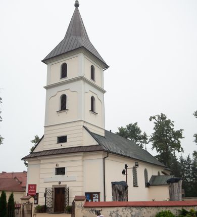 Zdjęcie nr 1: Kościół orientowany, murowany, jednonawowy, z trójbocznie zamkniętym prezbiterium z zakrystią od północy i kruchtą przylegającą do nawy od południa. Prezbiterium jest niższe i węższe od nawy, obie części mają gładkie ściany przeprute jedynie oknami w kształcie stojącego prostokąta zamkniętego łukiem półkolistym – cztery w prezbiterium, sześć w nawie. Sklepienia obu części zwierciadlane. Od południa chór o prostej balustradzie, wsparty na dwóch kolumnach. Ściany pokrywa polichromia ze scenami i cytatami z Pisma Świętego, postaciami świętych oraz żyjących, a także o motywach dekoracyjnych – roślinnych. Do około jednej czwartej wysokości ścian okładzina.  Zachodnią elewację frontową kościoła tworzy trójosiowa, wieżowa fasada. Oś kompozycji stanowi wysunięta ryzalitowo czterokondygnacyjna wieża. Ściana czołowa wieży dekorowana w pierwszej i drugiej kondygnacji boniowaniem i oknami w kształcie leżącego prostokąta osłoniętymi ozdobną kratą, z portalem o wykroju prostokątnym, ponad którym napis „DEO SOLI GLORIA”. W drugiej i trzeciej kondygnacji okna o wykroju stojącego prostokąta zamkniętego łukiem pełnym. Niżej w płycinie zwieńczonej łukiem nadwieszonym, wyżej w prostokątnej. Kondygnacje rozdzielone za pomocą masywnych gzymsów. Całość zwieńczona dachem namiotowym z kulą i krzyżem. Osie boczne cofnięte w stosunku do wysuniętej wieży i zrytmizowane podziałem ramowym, wypełnione wklęsłą płyciną w formie wydłużonego, stojącego prostokąta. Nad gzymsem fragment przyczółka przysłonięty wieżą. Elewacje boczne i tylna ukształtowane jednorodnie, gładkie, przeprute jedynie oknami. Wszystkie dachy blaszane – nad nawą i kruchtą dwuspadowy, nad zakrystią pulpitowy, nad prezbiterium zamknięty wielobocznie. 
Wartymi uwagi elementami wyposażenia kościoła jest siedemnastowieczny ołtarz boczny prawy z późniejszymi o wiek wizerunkami św. Katarzyny i św. Wawrzyńca, bogato rzeźbiona ława kolatorska i siedemnastowieczna chrzcielnica. 