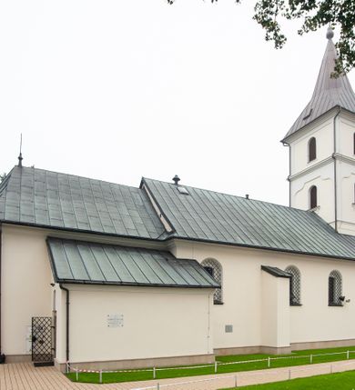 Zdjęcie nr 12: Kościół orientowany, murowany, jednonawowy, z trójbocznie zamkniętym prezbiterium z zakrystią od północy i kruchtą przylegającą do nawy od południa. Prezbiterium jest niższe i węższe od nawy, obie części mają gładkie ściany przeprute jedynie oknami w kształcie stojącego prostokąta zamkniętego łukiem półkolistym – cztery w prezbiterium, sześć w nawie. Sklepienia obu części zwierciadlane. Od południa chór o prostej balustradzie, wsparty na dwóch kolumnach. Ściany pokrywa polichromia ze scenami i cytatami z Pisma Świętego, postaciami świętych oraz żyjących, a także o motywach dekoracyjnych – roślinnych. Do około jednej czwartej wysokości ścian okładzina.  Zachodnią elewację frontową kościoła tworzy trójosiowa, wieżowa fasada. Oś kompozycji stanowi wysunięta ryzalitowo czterokondygnacyjna wieża. Ściana czołowa wieży dekorowana w pierwszej i drugiej kondygnacji boniowaniem i oknami w kształcie leżącego prostokąta osłoniętymi ozdobną kratą, z portalem o wykroju prostokątnym, ponad którym napis „DEO SOLI GLORIA”. W drugiej i trzeciej kondygnacji okna o wykroju stojącego prostokąta zamkniętego łukiem pełnym. Niżej w płycinie zwieńczonej łukiem nadwieszonym, wyżej w prostokątnej. Kondygnacje rozdzielone za pomocą masywnych gzymsów. Całość zwieńczona dachem namiotowym z kulą i krzyżem. Osie boczne cofnięte w stosunku do wysuniętej wieży i zrytmizowane podziałem ramowym, wypełnione wklęsłą płyciną w formie wydłużonego, stojącego prostokąta. Nad gzymsem fragment przyczółka przysłonięty wieżą. Elewacje boczne i tylna ukształtowane jednorodnie, gładkie, przeprute jedynie oknami. Wszystkie dachy blaszane – nad nawą i kruchtą dwuspadowy, nad zakrystią pulpitowy, nad prezbiterium zamknięty wielobocznie. 
Wartymi uwagi elementami wyposażenia kościoła jest siedemnastowieczny ołtarz boczny prawy z późniejszymi o wiek wizerunkami św. Katarzyny i św. Wawrzyńca, bogato rzeźbiona ława kolatorska i siedemnastowieczna chrzcielnica. 