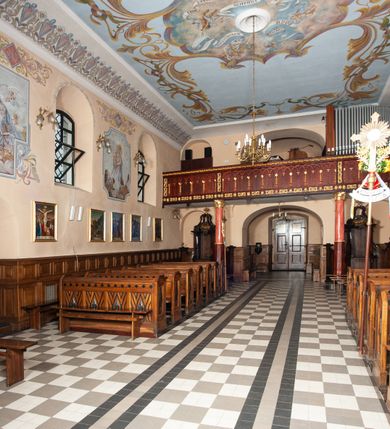 Zdjęcie nr 21: Kościół orientowany, murowany, jednonawowy, z trójbocznie zamkniętym prezbiterium z zakrystią od północy i kruchtą przylegającą do nawy od południa. Prezbiterium jest niższe i węższe od nawy, obie części mają gładkie ściany przeprute jedynie oknami w kształcie stojącego prostokąta zamkniętego łukiem półkolistym – cztery w prezbiterium, sześć w nawie. Sklepienia obu części zwierciadlane. Od południa chór o prostej balustradzie, wsparty na dwóch kolumnach. Ściany pokrywa polichromia ze scenami i cytatami z Pisma Świętego, postaciami świętych oraz żyjących, a także o motywach dekoracyjnych – roślinnych. Do około jednej czwartej wysokości ścian okładzina.  Zachodnią elewację frontową kościoła tworzy trójosiowa, wieżowa fasada. Oś kompozycji stanowi wysunięta ryzalitowo czterokondygnacyjna wieża. Ściana czołowa wieży dekorowana w pierwszej i drugiej kondygnacji boniowaniem i oknami w kształcie leżącego prostokąta osłoniętymi ozdobną kratą, z portalem o wykroju prostokątnym, ponad którym napis „DEO SOLI GLORIA”. W drugiej i trzeciej kondygnacji okna o wykroju stojącego prostokąta zamkniętego łukiem pełnym. Niżej w płycinie zwieńczonej łukiem nadwieszonym, wyżej w prostokątnej. Kondygnacje rozdzielone za pomocą masywnych gzymsów. Całość zwieńczona dachem namiotowym z kulą i krzyżem. Osie boczne cofnięte w stosunku do wysuniętej wieży i zrytmizowane podziałem ramowym, wypełnione wklęsłą płyciną w formie wydłużonego, stojącego prostokąta. Nad gzymsem fragment przyczółka przysłonięty wieżą. Elewacje boczne i tylna ukształtowane jednorodnie, gładkie, przeprute jedynie oknami. Wszystkie dachy blaszane – nad nawą i kruchtą dwuspadowy, nad zakrystią pulpitowy, nad prezbiterium zamknięty wielobocznie. 
Wartymi uwagi elementami wyposażenia kościoła jest siedemnastowieczny ołtarz boczny prawy z późniejszymi o wiek wizerunkami św. Katarzyny i św. Wawrzyńca, bogato rzeźbiona ława kolatorska i siedemnastowieczna chrzcielnica. 