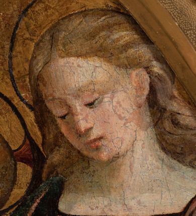 Zdjęcie nr 11: Obraz w formie medalionu w kwadratowej ramie z przedstawieniem Matki Boskiej z Dzieciątkiem oraz dwóch adorujących aniołów. W centrum kompozycji Matka Boska z pochyloną w lewą stronę głową, ukazana jako siedząca, która lewą dłonią przytrzymuje stojące Dzieciątko, a w prawej trzyma chusteczkę. Twarz ma trójkątną o małych oczach i ustach, z długim nosem. Ubrana jest w czerwoną suknię oraz niebieski płaszcz z zieloną podszewką, spięty pod szyją złotą klamrą, zarzucony na głowę i otulający całą postać. Dzieciątko ukazane nagie, zwrócone delikatnie w prawo, lewą rączkę opiera na biodrze, a prawą błogosławi. Twarz ma pełną o rysach dziecięcych, silnie zarumienioną na policzkach, okoloną jasnymi włosami, wokół głowy ma nimb krzyżowy. Po bokach stoją aniołowie, delikatnie pochyleni ku środkowi. Anioł po lewej stronie ma skrzyżowane na piersi ręce. Ubrany jest w żółtą suknię z długimi rękawami oraz niebieską tunikę. Anioł po prawej stronie składa ręce w geście modlitwy. Jets ubrany w brązową suknię z długimi rękawami oraz czerwoną tunikę. Obaj mają delikatne rysy twarzy oraz długie i jasne włosy. Maria oraz aniołowie mają wokół głów koliste nimby nakreślone czarnym konturem. Tło jednolite, złocone. Rama kwadratowa z polem obrazowym w kształcie medalionu, zdobiona na brzegu motywem skręconego sznura, a w przyłuczach stylizowanymi liśćmi akantu. Na odwrociu kartka z drukowanym napisem „Ze zbiorów księdza Jana kniazia z Kozielska Puzyny księcia biskupa krakowskiego, no 11”.
