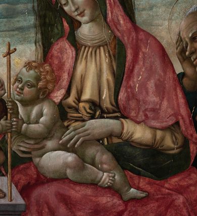 Zdjęcie nr 5: Obraz w formie medalionu w kwadratowej ramie z przedstawieniem Matki Boskiej z Dzieciątkiem, ze św. Janem Chrzcicielem i św. Józefem. W centrum kompozycji Matka Boska ukazana jako siedząca z głową delikatnie pochyloną w prawo, dłońmi przytrzymuje siedzące Dzieciątko. Twarz ma trójkątną o małych, półprzymkniętych oczach; długim i prostym nosie oraz wąskich ustach. Ubrana jest w jasnobrązową suknię oraz czerwony płaszcz z zieloną podszewką, zarzucony na głowę i otulający całą postać, na głowie ma  także biały welon. Dzieciątko w pozycji półleżącej, ukazane nagie, zwrócone ku św. Janowi Chrzcicielowi i obejmujące go prawą rączką za szyję. Twarz ma pełną o małych oczach, małym nosie i ustach, silnie zarumienioną na policzkach, okoloną jasnymi i kręconymi włosami. Z lewej strony obrazu na wysokim, kamiennym cokole przyklęka na prawe kolano  św. Jan Chrzciciel, ukazany jako kilkuletnie dziecko, zwrócony trzy czwarte w lewo, z delikatnie uniesioną głową. W rękach trzyma laskę zakończoną krzyżem. Twarz ma dziecięcą o pełnych policzkach, małych oczach skierowanych w górę, małym nosie i ustach, okoloną jasnymi i krótkimi włosami. Jego ciało przesłonięte jest w partii torsu i nóg brązową melotą. Po prawej stronie obrazu stoi św. Józef, zwrócony trzy czwarte w prawo, lewą ręką wspiera się na kiju pasterskim, a prawą trzyma się za głowę. Ubrany jest w niebieską suknię i żółty płaszcz. Twarz szeroka z wydatnym podbródkiem i długim nosem, włosy siwe i krótkie. Wokół głów św. Józef, Matka Boska i św. Jan Chrzciciel mają złote, okrągłe nimby. Karnacje postaci w odcieniu szarym, bladym; kolorystyka pastelowa. W oddali pejzaż górki, niebo różowo-niebieskie. Za Matką Boską pionowy, zielony pas kotary (?). Rama kwadratowa z polem obrazowym w kształcie medalionu, zdobiona na brzegu pasami kimationu, profilowaniem, a w przyłuczach stylizowanymi liśćmi akantu. 
