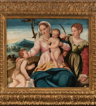 Zdjęcie nr 2: Obraz w formie leżącego prostokąta z przedstawieniem Matki Boskiej z Dzieciątkiem ze św. Janem Chrzcicielem i św. Katarzyną Aleksandryjską. W centrum kompozycji Matka Boska ukazana jako siedząca, lewą ręką przytrzymuje siedzące Dzieciątko, oparte o jej lewe ramię. Twarz ma owalną o małych, półprzymkniętych oczach, długim i prostym nosie oraz wąskich ustach, okoloną jasnymi włosami, ukrytymi pod welonem. Ubrana jest w jasnoróżową suknię oraz niebieski płaszcz z żółtą podszewką, zarzucony na plecy i lewe ramię, zakrywający kolana. Na głowie ma biały welon opadający na prawe ramię i plecy. Dzieciątko w pozycji stojącej, zwrócone w trzech czwartych w prawo, nagie, prawą rękę unosi w geście błogosławieństwa. Twarz ma kwadratową o przymkniętych oczach, małym nosie i ustach, okoloną jasnymi i kręconymi włosami. U nóg Matki Boskiej, z lewej strony obrazu podchodzi św. Jan Chrzciciel, ukazany jako kilkuletnie dziecko, z prawego profilu, z delikatnie uniesioną głową. W lewej ręce trzyma laskę zakończoną krzyżem. Twarz ma szeroką, o pełnych policzkach, małych oczach skierowanych w górę, małym nosie i ustach, okoloną jasnymi i krótkimi włosami. Jego ciało przesłonięte jest w partii torsu brązową melotą. Obok niego znajduje się biały baranek. Po prawej stronie obrazu stoi św. Katarzyna Aleksandryjska, wspierająca się lewą ręką o koło, a w prawej, ugiętej w łokciu trzyma palmę męczeństwa. Twarz ma owalną o małych ustach, długim nosie i małych oczach, okoloną jasnymi włosami, splecionymi w warkocze dookoła głowy i spiętymi wstążkami. Ubrana jest w oliwkowozieloną suknię z dekoltem i czerwonymi rękawami. W tle krajobraz górski i błękitne niebo. Kolorystyka jasna, pastelowa, szaty silnie przemalowane. Rama drewniana, rzeźbiona, zdobiona kimationem i liśćmi akantu. Na odwrociu przyklejona karteczka z drukowanym napisem „Księdza Jana kniazia z Kozielska Puzyny księcia biskupa krakowskiego, no 16”.