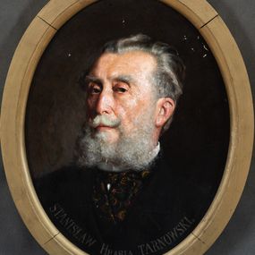 Zdjęcie nr 1: Obraz w kształcie stojącego owalu z przedstawieniem hrabiego Stanisława Tarnowskiego. Ujęcie portretowe, z torsem  ujętym frontalnie i głową zwróconą lekko w prawo. Hrabia ma podłużną twarz o małych oczach, delikatnie półokrągłym profilu nosa i wąskich ustach. Zarost tworzą podwinięte na końcach wąsy i długa, rozchodząca się na boki siwa broda, włosy ma zaczesane do tyłu. Jest ubrany w białą koszulę granatowy fular w złote wzory i czarną marynarkę. Przy dolnej krawędzi obrazu napis „STANISŁAW Hrabia TARNOWSKI. / m(alował): J(an) Bąkowski 99.”. 
