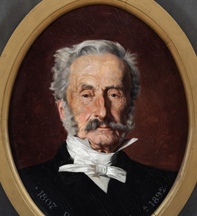 Zdjęcie nr 1: Obraz w kształcie stojącego owalu z przedstawieniem Pawła Popiela. Ujęcie portretowe, z torsem  zwróconym lekko w lewo i głową frontalnie. Popiel ma trójkątną twarz o małych oczach, garbatym nosie i wąskich ustach zakrytych częściowo. Zarost tworzą siwe wąsy i bokobrody, włosy ma zaczesane do tyłu. Jest ubrany w białą koszulę przewiązaną białą apaszką i czarną marynarkę. Przy dolnej krawędzi obrazu napis „*1807 PAWEŁ POPIEL +1892”. 