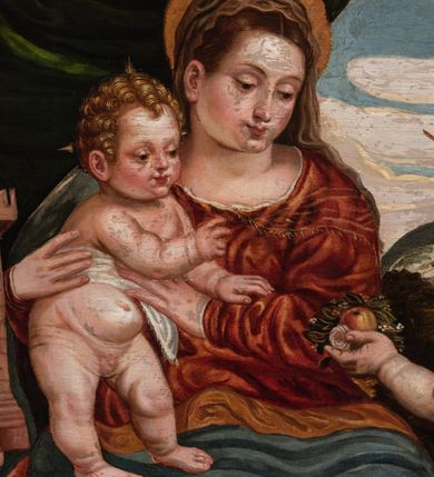 Zdjęcie nr 2: Obraz przedstawiający Matkę Boską z Dzieciątkiem stojącym na jej prawym udzie, siedzącą między stojącymi św. Barbarą z lewej strony i młodym św. Janem Chrzcicielem z prawej. Maria spogląda na jabłko podawane Jezusowi przez św. Jana. Ma okrągłą twarz, ciemne oczy , wąski nos i małe usta. Jest ubrana w czerwoną suknię i niebieski płaszcz ze złotym podbiciem. Jezus sięga w stronę jabłka, ma małą, okrągłą twarz i jasne włosy zwinięte w loki, jest przepasany białą tkaniną powyżej pasa. Święty Jan Chrzciciel został ukazany z profilu, jedną ręką podaje jabłko, w drugiej trzyma krzyż. Ma podłużną twarz z wysokim czołem, małym nosem i ciemnymi oczami, jest ubrany w skórę. Stojąca po drugiej stronie św. Barbara została ukazana lekko z tyłu, w rękach trzyma wieżę, twarz zwraca ku scenie, ma ciemne oczy, wśki nos i małe usta, włosy misternie zaplecione. Jest ubrana w ciemnozieloną suknię z czerwonymi rękawami i przezroczystym materiałem przy dekolcie. Biodra otacza żółty płaszcz. Tło sceny z lewej strony stanowi kotara, z prawej rozległy krajobraz.