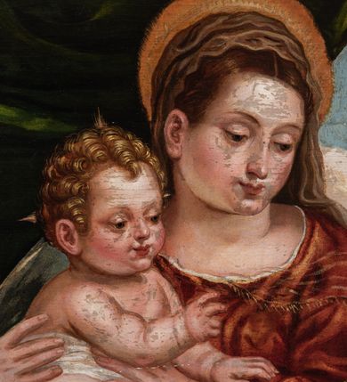 Zdjęcie nr 3: Obraz przedstawiający Matkę Boską z Dzieciątkiem stojącym na jej prawym udzie, siedzącą między stojącymi św. Barbarą z lewej strony i młodym św. Janem Chrzcicielem z prawej. Maria spogląda na jabłko podawane Jezusowi przez św. Jana. Ma okrągłą twarz, ciemne oczy , wąski nos i małe usta. Jest ubrana w czerwoną suknię i niebieski płaszcz ze złotym podbiciem. Jezus sięga w stronę jabłka, ma małą, okrągłą twarz i jasne włosy zwinięte w loki, jest przepasany białą tkaniną powyżej pasa. Święty Jan Chrzciciel został ukazany z profilu, jedną ręką podaje jabłko, w drugiej trzyma krzyż. Ma podłużną twarz z wysokim czołem, małym nosem i ciemnymi oczami, jest ubrany w skórę. Stojąca po drugiej stronie św. Barbara została ukazana lekko z tyłu, w rękach trzyma wieżę, twarz zwraca ku scenie, ma ciemne oczy, wśki nos i małe usta, włosy misternie zaplecione. Jest ubrana w ciemnozieloną suknię z czerwonymi rękawami i przezroczystym materiałem przy dekolcie. Biodra otacza żółty płaszcz. Tło sceny z lewej strony stanowi kotara, z prawej rozległy krajobraz.