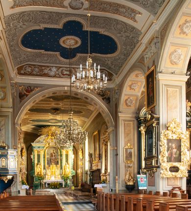 Zdjęcie nr 75: Kościół orientowany, murowany, trzynawowy. Typ halowy, z węższym, prostokątnym prezbiterium zamkniętym trójbocznie oraz z wieżą wbudowaną w zachodnią fasadę. Do prezbiterium od północy przylega zakrystia (do niej od zachodu klatka schodowa wiodąca do skarbca na piętrze), od południa natomiast kaplica Morsztynów z XVII wieku. Kaplica na planie prostokąta zamkniętego trójbocznie, z niszami w ściętych narożach, pod nią sklepiona krypta grobowa, opięta pilastrami wewnątrz i na zewnątrz. Od południa do korpusu przylega kruchta stanowiąca również kaplicę Matki Boskiej Pocieszenia. Korpus czteroprzęsłowy, nawy oddzielają arkady wsparte na filarach, pierwsze stanowią podparcie dla chóru. Nad nawami i prezbiterium strop imitujący sklepienie, na którym malowana dekoracja imitująca gurty, plafony oraz stiuki. Dekoracja ścian powtarza podziały wyznaczone przez arkady, namalowano na nich pilastry podtrzymujące belkowanie. W prezbiterium dwa okna usytuowane niedaleko ołtarza, w nawie osiem, wszystkie w kształcie stojącego prostokąta zamkniętego półkoliście, wypełnione witrażami z dekoracją geometryczną. Główne wejście od zachodu, drugie od północy, trzecie symetrycznie od południa przez kruchtę sklepioną kopułą, kolejne trzy do prezbiterium, od południa przez zakrystię i od północy przez kruchtę. 
Fasada zachodnia na cokole, podzielona gzymsami i lizenami, z wieżą zakończoną hełmem. Na osi drzwi w kształcie stojącego prostokąta flankowane prostokątnymi oknami, powyżej trzecie, większe okno zamknięte łukiem odcinkowym; kondygnację wieńczy gzyms. Druga kondygnacja powtarza podziały pierwszej. W środkowej osi okulus, powyżej dwudzielne okno zamknięte półkoliście. Nad nim tarcza zegara, kolejne dwie na ścianach bocznych. Kondygnacja ograniczona po bokach spływali wolutowymi i obeliskami zakończonymi kulami; przechodzi w wieżę. Powyżej gzyms podtrzymywany kroksztynami. Ostatnia kondygnacja o artykulacji ramowej z balkonami z każdej strony, powyżej wieńczącego gzymsu. Pozostałe elewacje na cokole, kontynuują podziały  lizenowo-ramowe, artykulacją podkreślają okna. Kaplica Morsztynów opięta pilastrami z głowicami, prezbiterium oszkarpowane. Dach nad nawą główną, kaplicą i prezbiterium dwuspadowy, na kruchtą południową kopuła, na wieży ozdobny hełm dołem wklęsły, dekorowany wolutami. Powyżej kopuła, na której latarnia przepruta arkadami i zwieńczona przewężoną w środku kopułą zakończoną ostrosłupem z kulą i krzyżem. 
Do najcenniejszych zabytków świątyni należą m.in. zaprojektowana przez Jana Delamarsa kaplica Morsztynów dekorowana stiukami z 1693 roku autorstwa Baltazara Fontany. Wewnątrz niej warto zwrócić uwagę na osiemnastowieczny ołtarz z przedstawieniem Oblicza Chrystusa i rzeźbionym antepedium. W ołtarz Ukrzyżowania znajdujący się w północnej nawie kościoła wkomponowano gotyckie rzeźby św. Jana i Marii. 