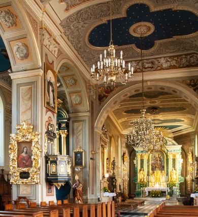 Zdjęcie nr 76: Kościół orientowany, murowany, trzynawowy. Typ halowy, z węższym, prostokątnym prezbiterium zamkniętym trójbocznie oraz z wieżą wbudowaną w zachodnią fasadę. Do prezbiterium od północy przylega zakrystia (do niej od zachodu klatka schodowa wiodąca do skarbca na piętrze), od południa natomiast kaplica Morsztynów z XVII wieku. Kaplica na planie prostokąta zamkniętego trójbocznie, z niszami w ściętych narożach, pod nią sklepiona krypta grobowa, opięta pilastrami wewnątrz i na zewnątrz. Od południa do korpusu przylega kruchta stanowiąca również kaplicę Matki Boskiej Pocieszenia. Korpus czteroprzęsłowy, nawy oddzielają arkady wsparte na filarach, pierwsze stanowią podparcie dla chóru. Nad nawami i prezbiterium strop imitujący sklepienie, na którym malowana dekoracja imitująca gurty, plafony oraz stiuki. Dekoracja ścian powtarza podziały wyznaczone przez arkady, namalowano na nich pilastry podtrzymujące belkowanie. W prezbiterium dwa okna usytuowane niedaleko ołtarza, w nawie osiem, wszystkie w kształcie stojącego prostokąta zamkniętego półkoliście, wypełnione witrażami z dekoracją geometryczną. Główne wejście od zachodu, drugie od północy, trzecie symetrycznie od południa przez kruchtę sklepioną kopułą, kolejne trzy do prezbiterium, od południa przez zakrystię i od północy przez kruchtę. 
Fasada zachodnia na cokole, podzielona gzymsami i lizenami, z wieżą zakończoną hełmem. Na osi drzwi w kształcie stojącego prostokąta flankowane prostokątnymi oknami, powyżej trzecie, większe okno zamknięte łukiem odcinkowym; kondygnację wieńczy gzyms. Druga kondygnacja powtarza podziały pierwszej. W środkowej osi okulus, powyżej dwudzielne okno zamknięte półkoliście. Nad nim tarcza zegara, kolejne dwie na ścianach bocznych. Kondygnacja ograniczona po bokach spływali wolutowymi i obeliskami zakończonymi kulami; przechodzi w wieżę. Powyżej gzyms podtrzymywany kroksztynami. Ostatnia kondygnacja o artykulacji ramowej z balkonami z każdej strony, powyżej wieńczącego gzymsu. Pozostałe elewacje na cokole, kontynuują podziały  lizenowo-ramowe, artykulacją podkreślają okna. Kaplica Morsztynów opięta pilastrami z głowicami, prezbiterium oszkarpowane. Dach nad nawą główną, kaplicą i prezbiterium dwuspadowy, na kruchtą południową kopuła, na wieży ozdobny hełm dołem wklęsły, dekorowany wolutami. Powyżej kopuła, na której latarnia przepruta arkadami i zwieńczona przewężoną w środku kopułą zakończoną ostrosłupem z kulą i krzyżem. 
Do najcenniejszych zabytków świątyni należą m.in. zaprojektowana przez Jana Delamarsa kaplica Morsztynów dekorowana stiukami z 1693 roku autorstwa Baltazara Fontany. Wewnątrz niej warto zwrócić uwagę na osiemnastowieczny ołtarz z przedstawieniem Oblicza Chrystusa i rzeźbionym antepedium. W ołtarz Ukrzyżowania znajdujący się w północnej nawie kościoła wkomponowano gotyckie rzeźby św. Jana i Marii. 