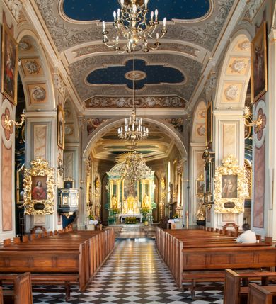 Zdjęcie nr 74: Kościół orientowany, murowany, trzynawowy. Typ halowy, z węższym, prostokątnym prezbiterium zamkniętym trójbocznie oraz z wieżą wbudowaną w zachodnią fasadę. Do prezbiterium od północy przylega zakrystia (do niej od zachodu klatka schodowa wiodąca do skarbca na piętrze), od południa natomiast kaplica Morsztynów z XVII wieku. Kaplica na planie prostokąta zamkniętego trójbocznie, z niszami w ściętych narożach, pod nią sklepiona krypta grobowa, opięta pilastrami wewnątrz i na zewnątrz. Od południa do korpusu przylega kruchta stanowiąca również kaplicę Matki Boskiej Pocieszenia. Korpus czteroprzęsłowy, nawy oddzielają arkady wsparte na filarach, pierwsze stanowią podparcie dla chóru. Nad nawami i prezbiterium strop imitujący sklepienie, na którym malowana dekoracja imitująca gurty, plafony oraz stiuki. Dekoracja ścian powtarza podziały wyznaczone przez arkady, namalowano na nich pilastry podtrzymujące belkowanie. W prezbiterium dwa okna usytuowane niedaleko ołtarza, w nawie osiem, wszystkie w kształcie stojącego prostokąta zamkniętego półkoliście, wypełnione witrażami z dekoracją geometryczną. Główne wejście od zachodu, drugie od północy, trzecie symetrycznie od południa przez kruchtę sklepioną kopułą, kolejne trzy do prezbiterium, od południa przez zakrystię i od północy przez kruchtę. 
Fasada zachodnia na cokole, podzielona gzymsami i lizenami, z wieżą zakończoną hełmem. Na osi drzwi w kształcie stojącego prostokąta flankowane prostokątnymi oknami, powyżej trzecie, większe okno zamknięte łukiem odcinkowym; kondygnację wieńczy gzyms. Druga kondygnacja powtarza podziały pierwszej. W środkowej osi okulus, powyżej dwudzielne okno zamknięte półkoliście. Nad nim tarcza zegara, kolejne dwie na ścianach bocznych. Kondygnacja ograniczona po bokach spływali wolutowymi i obeliskami zakończonymi kulami; przechodzi w wieżę. Powyżej gzyms podtrzymywany kroksztynami. Ostatnia kondygnacja o artykulacji ramowej z balkonami z każdej strony, powyżej wieńczącego gzymsu. Pozostałe elewacje na cokole, kontynuują podziały  lizenowo-ramowe, artykulacją podkreślają okna. Kaplica Morsztynów opięta pilastrami z głowicami, prezbiterium oszkarpowane. Dach nad nawą główną, kaplicą i prezbiterium dwuspadowy, na kruchtą południową kopuła, na wieży ozdobny hełm dołem wklęsły, dekorowany wolutami. Powyżej kopuła, na której latarnia przepruta arkadami i zwieńczona przewężoną w środku kopułą zakończoną ostrosłupem z kulą i krzyżem. 
Do najcenniejszych zabytków świątyni należą m.in. zaprojektowana przez Jana Delamarsa kaplica Morsztynów dekorowana stiukami z 1693 roku autorstwa Baltazara Fontany. Wewnątrz niej warto zwrócić uwagę na osiemnastowieczny ołtarz z przedstawieniem Oblicza Chrystusa i rzeźbionym antepedium. W ołtarz Ukrzyżowania znajdujący się w północnej nawie kościoła wkomponowano gotyckie rzeźby św. Jana i Marii. 