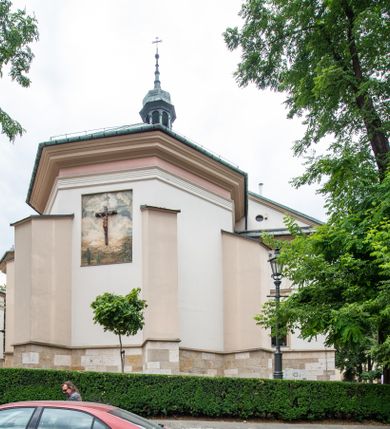 Zdjęcie nr 44: Kościół orientowany, murowany, trzynawowy. Typ halowy, z węższym, prostokątnym prezbiterium zamkniętym trójbocznie oraz z wieżą wbudowaną w zachodnią fasadę. Do prezbiterium od północy przylega zakrystia (do niej od zachodu klatka schodowa wiodąca do skarbca na piętrze), od południa natomiast kaplica Morsztynów z XVII wieku. Kaplica na planie prostokąta zamkniętego trójbocznie, z niszami w ściętych narożach, pod nią sklepiona krypta grobowa, opięta pilastrami wewnątrz i na zewnątrz. Od południa do korpusu przylega kruchta stanowiąca również kaplicę Matki Boskiej Pocieszenia. Korpus czteroprzęsłowy, nawy oddzielają arkady wsparte na filarach, pierwsze stanowią podparcie dla chóru. Nad nawami i prezbiterium strop imitujący sklepienie, na którym malowana dekoracja imitująca gurty, plafony oraz stiuki. Dekoracja ścian powtarza podziały wyznaczone przez arkady, namalowano na nich pilastry podtrzymujące belkowanie. W prezbiterium dwa okna usytuowane niedaleko ołtarza, w nawie osiem, wszystkie w kształcie stojącego prostokąta zamkniętego półkoliście, wypełnione witrażami z dekoracją geometryczną. Główne wejście od zachodu, drugie od północy, trzecie symetrycznie od południa przez kruchtę sklepioną kopułą, kolejne trzy do prezbiterium, od południa przez zakrystię i od północy przez kruchtę. 
Fasada zachodnia na cokole, podzielona gzymsami i lizenami, z wieżą zakończoną hełmem. Na osi drzwi w kształcie stojącego prostokąta flankowane prostokątnymi oknami, powyżej trzecie, większe okno zamknięte łukiem odcinkowym; kondygnację wieńczy gzyms. Druga kondygnacja powtarza podziały pierwszej. W środkowej osi okulus, powyżej dwudzielne okno zamknięte półkoliście. Nad nim tarcza zegara, kolejne dwie na ścianach bocznych. Kondygnacja ograniczona po bokach spływali wolutowymi i obeliskami zakończonymi kulami; przechodzi w wieżę. Powyżej gzyms podtrzymywany kroksztynami. Ostatnia kondygnacja o artykulacji ramowej z balkonami z każdej strony, powyżej wieńczącego gzymsu. Pozostałe elewacje na cokole, kontynuują podziały  lizenowo-ramowe, artykulacją podkreślają okna. Kaplica Morsztynów opięta pilastrami z głowicami, prezbiterium oszkarpowane. Dach nad nawą główną, kaplicą i prezbiterium dwuspadowy, na kruchtą południową kopuła, na wieży ozdobny hełm dołem wklęsły, dekorowany wolutami. Powyżej kopuła, na której latarnia przepruta arkadami i zwieńczona przewężoną w środku kopułą zakończoną ostrosłupem z kulą i krzyżem. 
Do najcenniejszych zabytków świątyni należą m.in. zaprojektowana przez Jana Delamarsa kaplica Morsztynów dekorowana stiukami z 1693 roku autorstwa Baltazara Fontany. Wewnątrz niej warto zwrócić uwagę na osiemnastowieczny ołtarz z przedstawieniem Oblicza Chrystusa i rzeźbionym antepedium. W ołtarz Ukrzyżowania znajdujący się w północnej nawie kościoła wkomponowano gotyckie rzeźby św. Jana i Marii. 