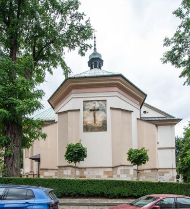 Zdjęcie nr 43: Kościół orientowany, murowany, trzynawowy. Typ halowy, z węższym, prostokątnym prezbiterium zamkniętym trójbocznie oraz z wieżą wbudowaną w zachodnią fasadę. Do prezbiterium od północy przylega zakrystia (do niej od zachodu klatka schodowa wiodąca do skarbca na piętrze), od południa natomiast kaplica Morsztynów z XVII wieku. Kaplica na planie prostokąta zamkniętego trójbocznie, z niszami w ściętych narożach, pod nią sklepiona krypta grobowa, opięta pilastrami wewnątrz i na zewnątrz. Od południa do korpusu przylega kruchta stanowiąca również kaplicę Matki Boskiej Pocieszenia. Korpus czteroprzęsłowy, nawy oddzielają arkady wsparte na filarach, pierwsze stanowią podparcie dla chóru. Nad nawami i prezbiterium strop imitujący sklepienie, na którym malowana dekoracja imitująca gurty, plafony oraz stiuki. Dekoracja ścian powtarza podziały wyznaczone przez arkady, namalowano na nich pilastry podtrzymujące belkowanie. W prezbiterium dwa okna usytuowane niedaleko ołtarza, w nawie osiem, wszystkie w kształcie stojącego prostokąta zamkniętego półkoliście, wypełnione witrażami z dekoracją geometryczną. Główne wejście od zachodu, drugie od północy, trzecie symetrycznie od południa przez kruchtę sklepioną kopułą, kolejne trzy do prezbiterium, od południa przez zakrystię i od północy przez kruchtę. 
Fasada zachodnia na cokole, podzielona gzymsami i lizenami, z wieżą zakończoną hełmem. Na osi drzwi w kształcie stojącego prostokąta flankowane prostokątnymi oknami, powyżej trzecie, większe okno zamknięte łukiem odcinkowym; kondygnację wieńczy gzyms. Druga kondygnacja powtarza podziały pierwszej. W środkowej osi okulus, powyżej dwudzielne okno zamknięte półkoliście. Nad nim tarcza zegara, kolejne dwie na ścianach bocznych. Kondygnacja ograniczona po bokach spływali wolutowymi i obeliskami zakończonymi kulami; przechodzi w wieżę. Powyżej gzyms podtrzymywany kroksztynami. Ostatnia kondygnacja o artykulacji ramowej z balkonami z każdej strony, powyżej wieńczącego gzymsu. Pozostałe elewacje na cokole, kontynuują podziały  lizenowo-ramowe, artykulacją podkreślają okna. Kaplica Morsztynów opięta pilastrami z głowicami, prezbiterium oszkarpowane. Dach nad nawą główną, kaplicą i prezbiterium dwuspadowy, na kruchtą południową kopuła, na wieży ozdobny hełm dołem wklęsły, dekorowany wolutami. Powyżej kopuła, na której latarnia przepruta arkadami i zwieńczona przewężoną w środku kopułą zakończoną ostrosłupem z kulą i krzyżem. 
Do najcenniejszych zabytków świątyni należą m.in. zaprojektowana przez Jana Delamarsa kaplica Morsztynów dekorowana stiukami z 1693 roku autorstwa Baltazara Fontany. Wewnątrz niej warto zwrócić uwagę na osiemnastowieczny ołtarz z przedstawieniem Oblicza Chrystusa i rzeźbionym antepedium. W ołtarz Ukrzyżowania znajdujący się w północnej nawie kościoła wkomponowano gotyckie rzeźby św. Jana i Marii. 