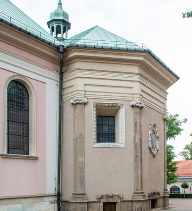 Zdjęcie nr 21: Kościół orientowany, murowany, trzynawowy. Typ halowy, z węższym, prostokątnym prezbiterium zamkniętym trójbocznie oraz z wieżą wbudowaną w zachodnią fasadę. Do prezbiterium od północy przylega zakrystia (do niej od zachodu klatka schodowa wiodąca do skarbca na piętrze), od południa natomiast kaplica Morsztynów z XVII wieku. Kaplica na planie prostokąta zamkniętego trójbocznie, z niszami w ściętych narożach, pod nią sklepiona krypta grobowa, opięta pilastrami wewnątrz i na zewnątrz. Od południa do korpusu przylega kruchta stanowiąca również kaplicę Matki Boskiej Pocieszenia. Korpus czteroprzęsłowy, nawy oddzielają arkady wsparte na filarach, pierwsze stanowią podparcie dla chóru. Nad nawami i prezbiterium strop imitujący sklepienie, na którym malowana dekoracja imitująca gurty, plafony oraz stiuki. Dekoracja ścian powtarza podziały wyznaczone przez arkady, namalowano na nich pilastry podtrzymujące belkowanie. W prezbiterium dwa okna usytuowane niedaleko ołtarza, w nawie osiem, wszystkie w kształcie stojącego prostokąta zamkniętego półkoliście, wypełnione witrażami z dekoracją geometryczną. Główne wejście od zachodu, drugie od północy, trzecie symetrycznie od południa przez kruchtę sklepioną kopułą, kolejne trzy do prezbiterium, od południa przez zakrystię i od północy przez kruchtę. 
Fasada zachodnia na cokole, podzielona gzymsami i lizenami, z wieżą zakończoną hełmem. Na osi drzwi w kształcie stojącego prostokąta flankowane prostokątnymi oknami, powyżej trzecie, większe okno zamknięte łukiem odcinkowym; kondygnację wieńczy gzyms. Druga kondygnacja powtarza podziały pierwszej. W środkowej osi okulus, powyżej dwudzielne okno zamknięte półkoliście. Nad nim tarcza zegara, kolejne dwie na ścianach bocznych. Kondygnacja ograniczona po bokach spływali wolutowymi i obeliskami zakończonymi kulami; przechodzi w wieżę. Powyżej gzyms podtrzymywany kroksztynami. Ostatnia kondygnacja o artykulacji ramowej z balkonami z każdej strony, powyżej wieńczącego gzymsu. Pozostałe elewacje na cokole, kontynuują podziały  lizenowo-ramowe, artykulacją podkreślają okna. Kaplica Morsztynów opięta pilastrami z głowicami, prezbiterium oszkarpowane. Dach nad nawą główną, kaplicą i prezbiterium dwuspadowy, na kruchtą południową kopuła, na wieży ozdobny hełm dołem wklęsły, dekorowany wolutami. Powyżej kopuła, na której latarnia przepruta arkadami i zwieńczona przewężoną w środku kopułą zakończoną ostrosłupem z kulą i krzyżem. 
Do najcenniejszych zabytków świątyni należą m.in. zaprojektowana przez Jana Delamarsa kaplica Morsztynów dekorowana stiukami z 1693 roku autorstwa Baltazara Fontany. Wewnątrz niej warto zwrócić uwagę na osiemnastowieczny ołtarz z przedstawieniem Oblicza Chrystusa i rzeźbionym antepedium. W ołtarz Ukrzyżowania znajdujący się w północnej nawie kościoła wkomponowano gotyckie rzeźby św. Jana i Marii. 