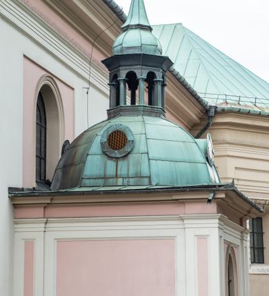 Zdjęcie nr 39: Kościół orientowany, murowany, trzynawowy. Typ halowy, z węższym, prostokątnym prezbiterium zamkniętym trójbocznie oraz z wieżą wbudowaną w zachodnią fasadę. Do prezbiterium od północy przylega zakrystia (do niej od zachodu klatka schodowa wiodąca do skarbca na piętrze), od południa natomiast kaplica Morsztynów z XVII wieku. Kaplica na planie prostokąta zamkniętego trójbocznie, z niszami w ściętych narożach, pod nią sklepiona krypta grobowa, opięta pilastrami wewnątrz i na zewnątrz. Od południa do korpusu przylega kruchta stanowiąca również kaplicę Matki Boskiej Pocieszenia. Korpus czteroprzęsłowy, nawy oddzielają arkady wsparte na filarach, pierwsze stanowią podparcie dla chóru. Nad nawami i prezbiterium strop imitujący sklepienie, na którym malowana dekoracja imitująca gurty, plafony oraz stiuki. Dekoracja ścian powtarza podziały wyznaczone przez arkady, namalowano na nich pilastry podtrzymujące belkowanie. W prezbiterium dwa okna usytuowane niedaleko ołtarza, w nawie osiem, wszystkie w kształcie stojącego prostokąta zamkniętego półkoliście, wypełnione witrażami z dekoracją geometryczną. Główne wejście od zachodu, drugie od północy, trzecie symetrycznie od południa przez kruchtę sklepioną kopułą, kolejne trzy do prezbiterium, od południa przez zakrystię i od północy przez kruchtę. 
Fasada zachodnia na cokole, podzielona gzymsami i lizenami, z wieżą zakończoną hełmem. Na osi drzwi w kształcie stojącego prostokąta flankowane prostokątnymi oknami, powyżej trzecie, większe okno zamknięte łukiem odcinkowym; kondygnację wieńczy gzyms. Druga kondygnacja powtarza podziały pierwszej. W środkowej osi okulus, powyżej dwudzielne okno zamknięte półkoliście. Nad nim tarcza zegara, kolejne dwie na ścianach bocznych. Kondygnacja ograniczona po bokach spływali wolutowymi i obeliskami zakończonymi kulami; przechodzi w wieżę. Powyżej gzyms podtrzymywany kroksztynami. Ostatnia kondygnacja o artykulacji ramowej z balkonami z każdej strony, powyżej wieńczącego gzymsu. Pozostałe elewacje na cokole, kontynuują podziały  lizenowo-ramowe, artykulacją podkreślają okna. Kaplica Morsztynów opięta pilastrami z głowicami, prezbiterium oszkarpowane. Dach nad nawą główną, kaplicą i prezbiterium dwuspadowy, na kruchtą południową kopuła, na wieży ozdobny hełm dołem wklęsły, dekorowany wolutami. Powyżej kopuła, na której latarnia przepruta arkadami i zwieńczona przewężoną w środku kopułą zakończoną ostrosłupem z kulą i krzyżem. 
Do najcenniejszych zabytków świątyni należą m.in. zaprojektowana przez Jana Delamarsa kaplica Morsztynów dekorowana stiukami z 1693 roku autorstwa Baltazara Fontany. Wewnątrz niej warto zwrócić uwagę na osiemnastowieczny ołtarz z przedstawieniem Oblicza Chrystusa i rzeźbionym antepedium. W ołtarz Ukrzyżowania znajdujący się w północnej nawie kościoła wkomponowano gotyckie rzeźby św. Jana i Marii. 