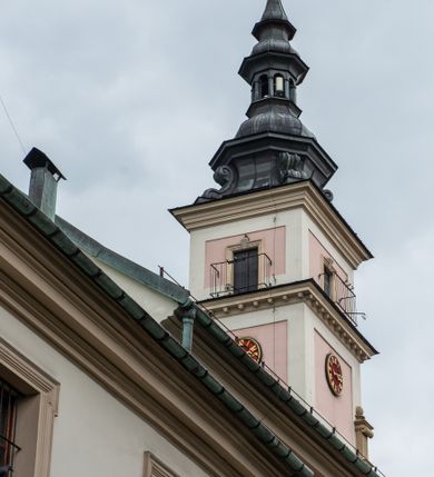 Zdjęcie nr 11: Kościół orientowany, murowany, trzynawowy. Typ halowy, z węższym, prostokątnym prezbiterium zamkniętym trójbocznie oraz z wieżą wbudowaną w zachodnią fasadę. Do prezbiterium od północy przylega zakrystia (do niej od zachodu klatka schodowa wiodąca do skarbca na piętrze), od południa natomiast kaplica Morsztynów z XVII wieku. Kaplica na planie prostokąta zamkniętego trójbocznie, z niszami w ściętych narożach, pod nią sklepiona krypta grobowa, opięta pilastrami wewnątrz i na zewnątrz. Od południa do korpusu przylega kruchta stanowiąca również kaplicę Matki Boskiej Pocieszenia. Korpus czteroprzęsłowy, nawy oddzielają arkady wsparte na filarach, pierwsze stanowią podparcie dla chóru. Nad nawami i prezbiterium strop imitujący sklepienie, na którym malowana dekoracja imitująca gurty, plafony oraz stiuki. Dekoracja ścian powtarza podziały wyznaczone przez arkady, namalowano na nich pilastry podtrzymujące belkowanie. W prezbiterium dwa okna usytuowane niedaleko ołtarza, w nawie osiem, wszystkie w kształcie stojącego prostokąta zamkniętego półkoliście, wypełnione witrażami z dekoracją geometryczną. Główne wejście od zachodu, drugie od północy, trzecie symetrycznie od południa przez kruchtę sklepioną kopułą, kolejne trzy do prezbiterium, od południa przez zakrystię i od północy przez kruchtę. 
Fasada zachodnia na cokole, podzielona gzymsami i lizenami, z wieżą zakończoną hełmem. Na osi drzwi w kształcie stojącego prostokąta flankowane prostokątnymi oknami, powyżej trzecie, większe okno zamknięte łukiem odcinkowym; kondygnację wieńczy gzyms. Druga kondygnacja powtarza podziały pierwszej. W środkowej osi okulus, powyżej dwudzielne okno zamknięte półkoliście. Nad nim tarcza zegara, kolejne dwie na ścianach bocznych. Kondygnacja ograniczona po bokach spływali wolutowymi i obeliskami zakończonymi kulami; przechodzi w wieżę. Powyżej gzyms podtrzymywany kroksztynami. Ostatnia kondygnacja o artykulacji ramowej z balkonami z każdej strony, powyżej wieńczącego gzymsu. Pozostałe elewacje na cokole, kontynuują podziały  lizenowo-ramowe, artykulacją podkreślają okna. Kaplica Morsztynów opięta pilastrami z głowicami, prezbiterium oszkarpowane. Dach nad nawą główną, kaplicą i prezbiterium dwuspadowy, na kruchtą południową kopuła, na wieży ozdobny hełm dołem wklęsły, dekorowany wolutami. Powyżej kopuła, na której latarnia przepruta arkadami i zwieńczona przewężoną w środku kopułą zakończoną ostrosłupem z kulą i krzyżem. 
Do najcenniejszych zabytków świątyni należą m.in. zaprojektowana przez Jana Delamarsa kaplica Morsztynów dekorowana stiukami z 1693 roku autorstwa Baltazara Fontany. Wewnątrz niej warto zwrócić uwagę na osiemnastowieczny ołtarz z przedstawieniem Oblicza Chrystusa i rzeźbionym antepedium. W ołtarz Ukrzyżowania znajdujący się w północnej nawie kościoła wkomponowano gotyckie rzeźby św. Jana i Marii. 