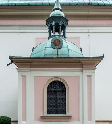 Zdjęcie nr 32: Kościół orientowany, murowany, trzynawowy. Typ halowy, z węższym, prostokątnym prezbiterium zamkniętym trójbocznie oraz z wieżą wbudowaną w zachodnią fasadę. Do prezbiterium od północy przylega zakrystia (do niej od zachodu klatka schodowa wiodąca do skarbca na piętrze), od południa natomiast kaplica Morsztynów z XVII wieku. Kaplica na planie prostokąta zamkniętego trójbocznie, z niszami w ściętych narożach, pod nią sklepiona krypta grobowa, opięta pilastrami wewnątrz i na zewnątrz. Od południa do korpusu przylega kruchta stanowiąca również kaplicę Matki Boskiej Pocieszenia. Korpus czteroprzęsłowy, nawy oddzielają arkady wsparte na filarach, pierwsze stanowią podparcie dla chóru. Nad nawami i prezbiterium strop imitujący sklepienie, na którym malowana dekoracja imitująca gurty, plafony oraz stiuki. Dekoracja ścian powtarza podziały wyznaczone przez arkady, namalowano na nich pilastry podtrzymujące belkowanie. W prezbiterium dwa okna usytuowane niedaleko ołtarza, w nawie osiem, wszystkie w kształcie stojącego prostokąta zamkniętego półkoliście, wypełnione witrażami z dekoracją geometryczną. Główne wejście od zachodu, drugie od północy, trzecie symetrycznie od południa przez kruchtę sklepioną kopułą, kolejne trzy do prezbiterium, od południa przez zakrystię i od północy przez kruchtę. 
Fasada zachodnia na cokole, podzielona gzymsami i lizenami, z wieżą zakończoną hełmem. Na osi drzwi w kształcie stojącego prostokąta flankowane prostokątnymi oknami, powyżej trzecie, większe okno zamknięte łukiem odcinkowym; kondygnację wieńczy gzyms. Druga kondygnacja powtarza podziały pierwszej. W środkowej osi okulus, powyżej dwudzielne okno zamknięte półkoliście. Nad nim tarcza zegara, kolejne dwie na ścianach bocznych. Kondygnacja ograniczona po bokach spływali wolutowymi i obeliskami zakończonymi kulami; przechodzi w wieżę. Powyżej gzyms podtrzymywany kroksztynami. Ostatnia kondygnacja o artykulacji ramowej z balkonami z każdej strony, powyżej wieńczącego gzymsu. Pozostałe elewacje na cokole, kontynuują podziały  lizenowo-ramowe, artykulacją podkreślają okna. Kaplica Morsztynów opięta pilastrami z głowicami, prezbiterium oszkarpowane. Dach nad nawą główną, kaplicą i prezbiterium dwuspadowy, na kruchtą południową kopuła, na wieży ozdobny hełm dołem wklęsły, dekorowany wolutami. Powyżej kopuła, na której latarnia przepruta arkadami i zwieńczona przewężoną w środku kopułą zakończoną ostrosłupem z kulą i krzyżem. 
Do najcenniejszych zabytków świątyni należą m.in. zaprojektowana przez Jana Delamarsa kaplica Morsztynów dekorowana stiukami z 1693 roku autorstwa Baltazara Fontany. Wewnątrz niej warto zwrócić uwagę na osiemnastowieczny ołtarz z przedstawieniem Oblicza Chrystusa i rzeźbionym antepedium. W ołtarz Ukrzyżowania znajdujący się w północnej nawie kościoła wkomponowano gotyckie rzeźby św. Jana i Marii. 