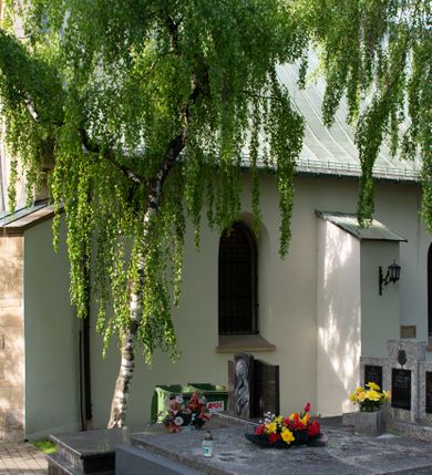 Zdjęcie nr 7: Kościół orientowany, jest budowlą murowaną z kamienia, na rzucie podłużnym. Korpus jednonawowy i dwuprzęsłowy. Do stosunkowo szerokiego, jednoprzęsłowego, zamkniętego trójbocznie prezbiterium od północy przylega zakrystia, a na osi kościoła, od zachodu kruchta. Prezbiterium przekryte jest sklepieniem krzyżowo-żebrowym, a nawa drewnianym sklepieniem kolebkowymi.  Przestrzeń prezbiterium od korpusu nawowego oddziela ostrołukowa arkada tęczowa i drewniana balustrada. Artykulację ścian na zewnątrz kościoła stanowi wieniec przypór ujmujących ściany i naroża korpusu nawowego i prezbiterium.  Do wnętrza prowadzą trzy otwory drzwiowe – jeden przez kruchtę w elewacji północnej, jeden w północnej ścianie korpusu nawowego i jeden przez zakrystię. Dwuskrzydłowe drzwi w kruchcie ujęte są portalem zamkniętym łukiem dwuramiennym, portale pozostałych otworów drzwiowych są ostrołukowe. Ściany korpusu nawowego i prezbiterium przeprute są smukłymi, ostrołukowymi oknami, w nawie wypełnionymi gomółkami, a w prezbiterium dekoracją maswerkową. W szczycie fasady para małych, wąskich okienek w kształcie stojących prostokątów, analogiczne w szczycie kruchty. Korpus nawowy, prezbiterium i zakrystia przekryte są jednym dachem dwuspadowym, wykonanym z blachy, kruchta także dachem dwuspadowym. Na połączeniu nawy i prezbiterium umieszczona jest wieżyczka na sygnaturkę, także obita blachą. Kolorystyka tynków kościoła utrzymana jest w kolorze białym, fasada i kruchta są kamienne. 