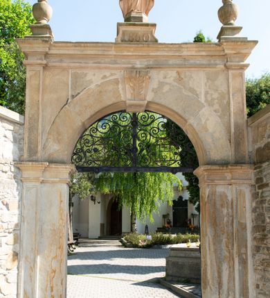 Zdjęcie nr 4: Kościół orientowany, jest budowlą murowaną z kamienia, na rzucie podłużnym. Korpus jednonawowy i dwuprzęsłowy. Do stosunkowo szerokiego, jednoprzęsłowego, zamkniętego trójbocznie prezbiterium od północy przylega zakrystia, a na osi kościoła, od zachodu kruchta. Prezbiterium przekryte jest sklepieniem krzyżowo-żebrowym, a nawa drewnianym sklepieniem kolebkowymi.  Przestrzeń prezbiterium od korpusu nawowego oddziela ostrołukowa arkada tęczowa i drewniana balustrada. Artykulację ścian na zewnątrz kościoła stanowi wieniec przypór ujmujących ściany i naroża korpusu nawowego i prezbiterium.  Do wnętrza prowadzą trzy otwory drzwiowe – jeden przez kruchtę w elewacji północnej, jeden w północnej ścianie korpusu nawowego i jeden przez zakrystię. Dwuskrzydłowe drzwi w kruchcie ujęte są portalem zamkniętym łukiem dwuramiennym, portale pozostałych otworów drzwiowych są ostrołukowe. Ściany korpusu nawowego i prezbiterium przeprute są smukłymi, ostrołukowymi oknami, w nawie wypełnionymi gomółkami, a w prezbiterium dekoracją maswerkową. W szczycie fasady para małych, wąskich okienek w kształcie stojących prostokątów, analogiczne w szczycie kruchty. Korpus nawowy, prezbiterium i zakrystia przekryte są jednym dachem dwuspadowym, wykonanym z blachy, kruchta także dachem dwuspadowym. Na połączeniu nawy i prezbiterium umieszczona jest wieżyczka na sygnaturkę, także obita blachą. Kolorystyka tynków kościoła utrzymana jest w kolorze białym, fasada i kruchta są kamienne. 