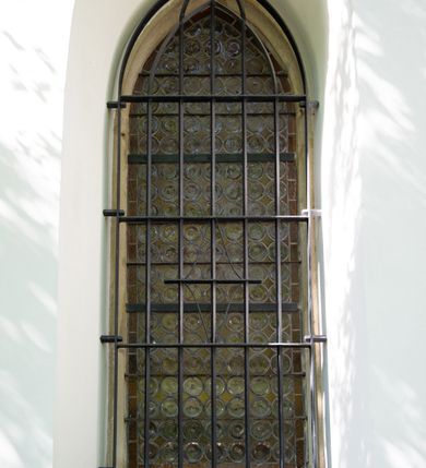 Zdjęcie nr 13: Kościół orientowany, jest budowlą murowaną z kamienia, na rzucie podłużnym. Korpus jednonawowy i dwuprzęsłowy. Do stosunkowo szerokiego, jednoprzęsłowego, zamkniętego trójbocznie prezbiterium od północy przylega zakrystia, a na osi kościoła, od zachodu kruchta. Prezbiterium przekryte jest sklepieniem krzyżowo-żebrowym, a nawa drewnianym sklepieniem kolebkowymi.  Przestrzeń prezbiterium od korpusu nawowego oddziela ostrołukowa arkada tęczowa i drewniana balustrada. Artykulację ścian na zewnątrz kościoła stanowi wieniec przypór ujmujących ściany i naroża korpusu nawowego i prezbiterium.  Do wnętrza prowadzą trzy otwory drzwiowe – jeden przez kruchtę w elewacji północnej, jeden w północnej ścianie korpusu nawowego i jeden przez zakrystię. Dwuskrzydłowe drzwi w kruchcie ujęte są portalem zamkniętym łukiem dwuramiennym, portale pozostałych otworów drzwiowych są ostrołukowe. Ściany korpusu nawowego i prezbiterium przeprute są smukłymi, ostrołukowymi oknami, w nawie wypełnionymi gomółkami, a w prezbiterium dekoracją maswerkową. W szczycie fasady para małych, wąskich okienek w kształcie stojących prostokątów, analogiczne w szczycie kruchty. Korpus nawowy, prezbiterium i zakrystia przekryte są jednym dachem dwuspadowym, wykonanym z blachy, kruchta także dachem dwuspadowym. Na połączeniu nawy i prezbiterium umieszczona jest wieżyczka na sygnaturkę, także obita blachą. Kolorystyka tynków kościoła utrzymana jest w kolorze białym, fasada i kruchta są kamienne. 